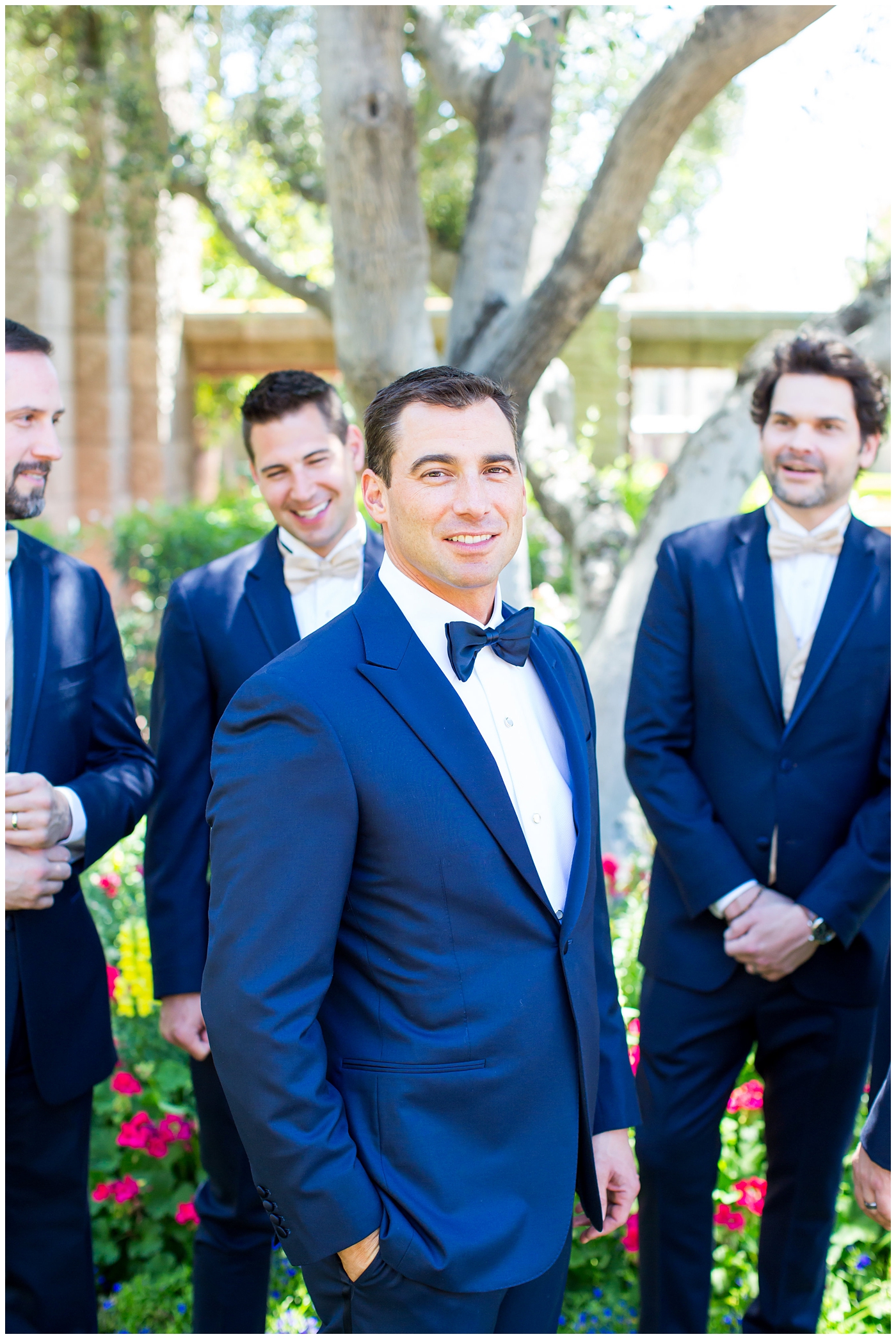 groom in navy neiman marcus and canali suit with blue bowtie with calla lilly boutonniere with groomsmen in suits and gold bowtie getting ready