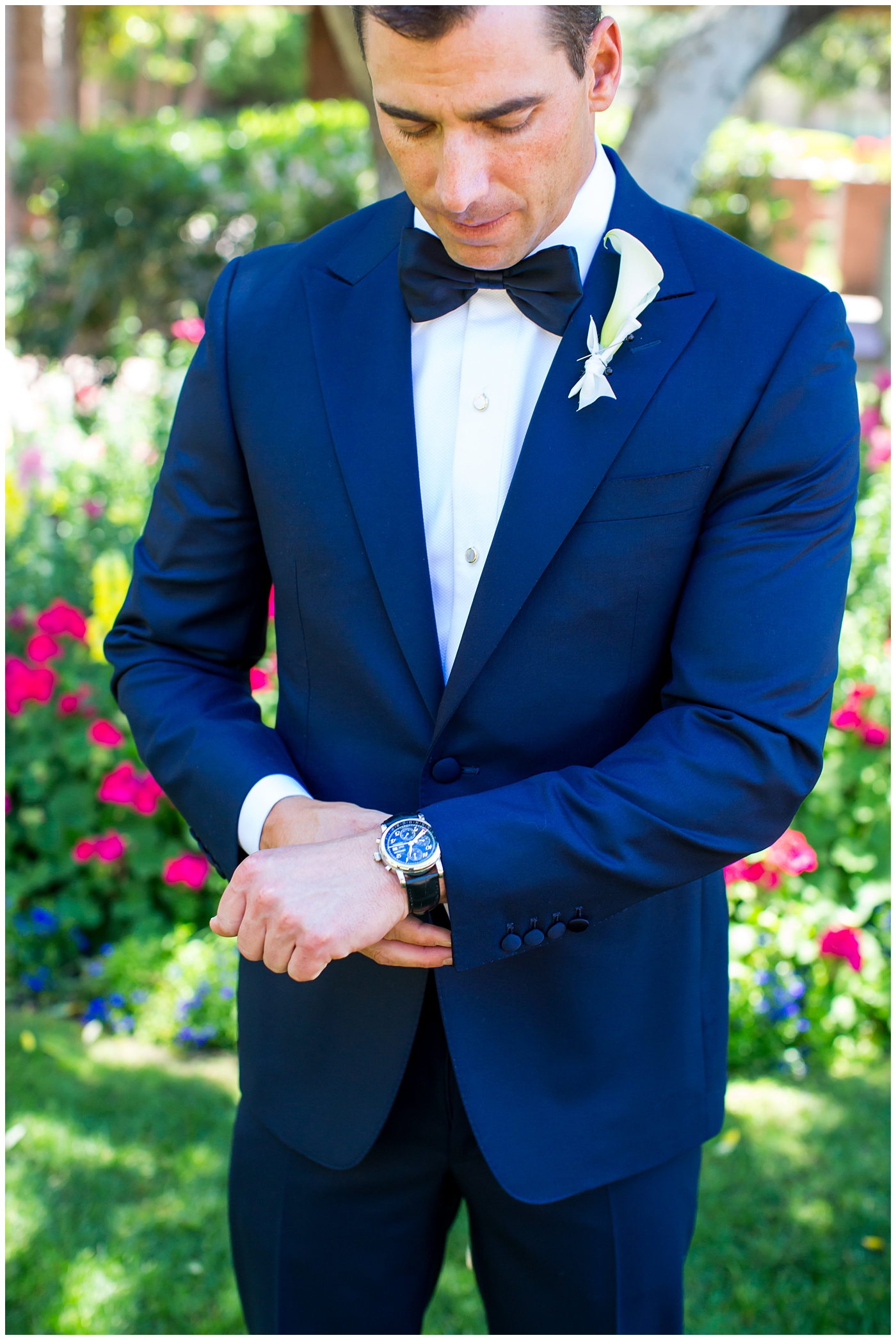 groom in navy neiman marcus and canali suit with blue bowtie with calla lilly boutonniere getting ready