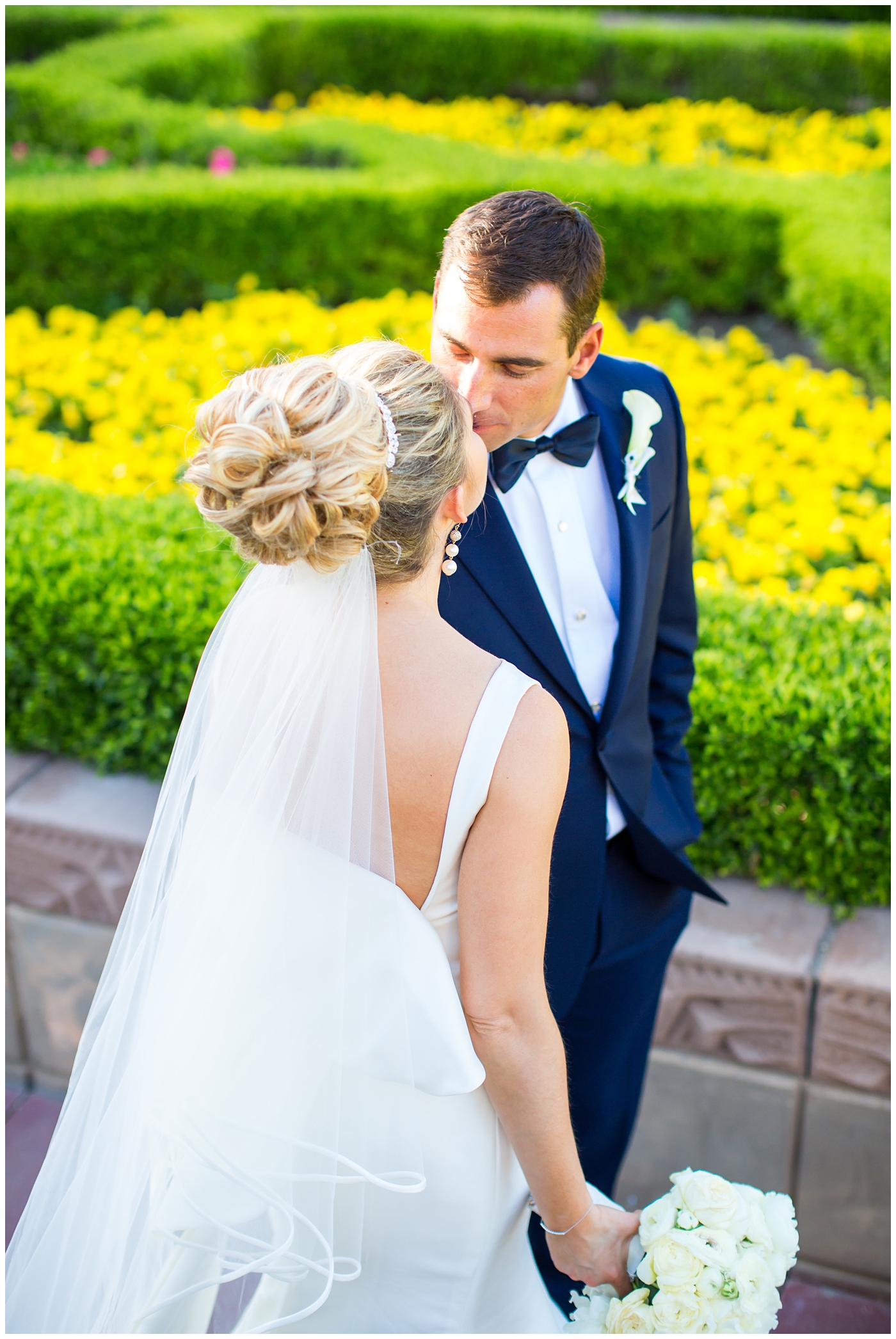 Bride in sareh nouri wedding dress with bow on the back and pink lip stick with all white flower bouquet with groom in navy neiman marcus and canali suit with bowtie with calla lilly boutonniere wedding day portrait