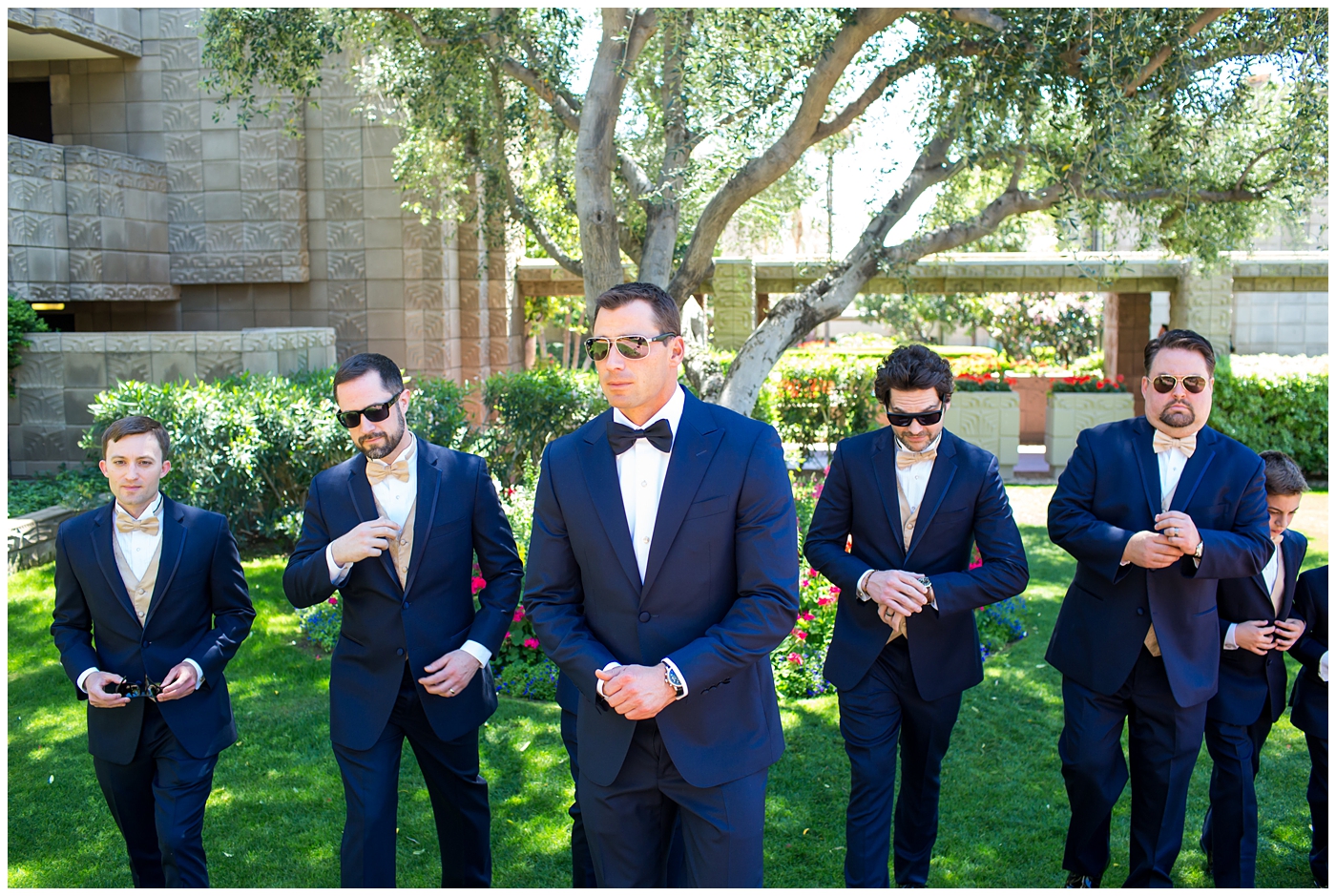 groom in navy neiman marcus and canali suit with blue bowtie with calla lilly boutonniere with groomsmen in suits and gold bowtie getting ready