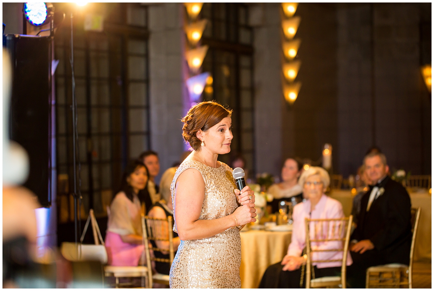 bridesmaid in gold sequin dress giving toast in ballroom wedding reception