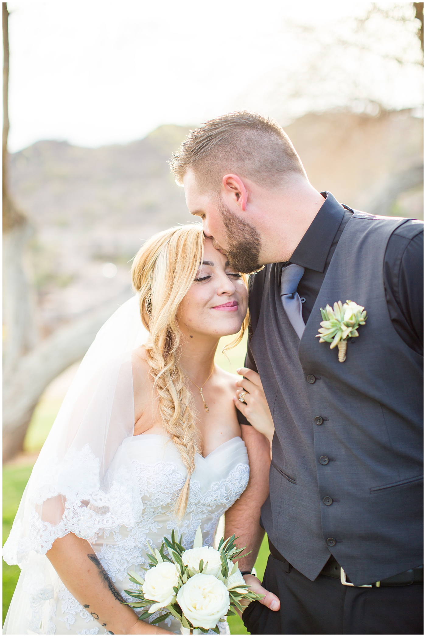 bride with fishtail braid and strapless dress with white rose and greenery bouquet with groom in black pants and vest and tie with rolled up shirt sleeves with succulent boutonniere wedding day portrait