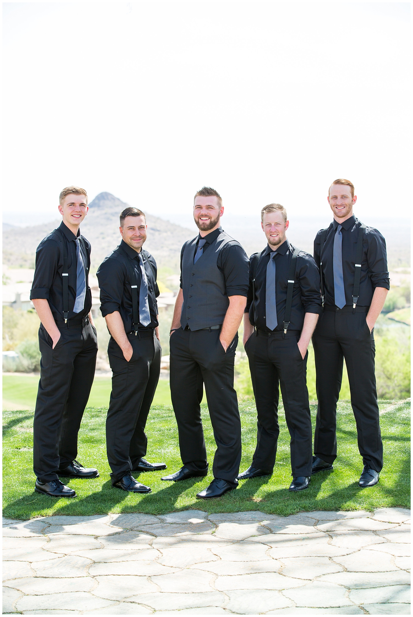 groom in black pants and vest and tie with rolled up shirt sleeves with succulent boutonniere with groomsmen in black pants with suspenders and tie wedding day bridal party portrait