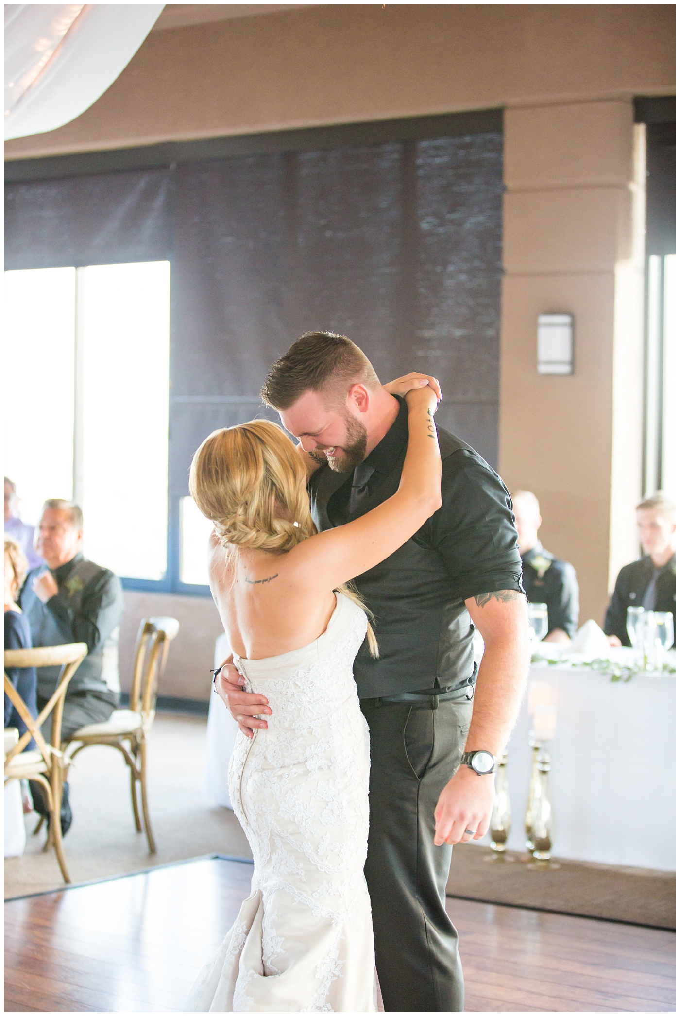 bride with fishtail braid and strapless dress with white rose and greenery bouquet with groom in black pants and vest and tie with rolled up shirt sleeves with succulent boutonniere wedding reception in ballroom first dance