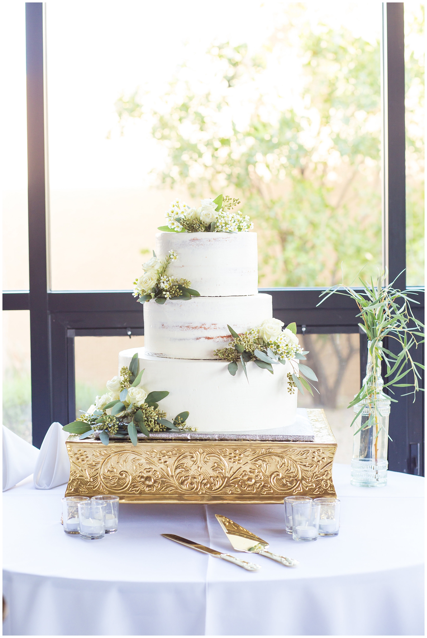 3 tier wedding cake with greenery and white roses wedding day reception detail