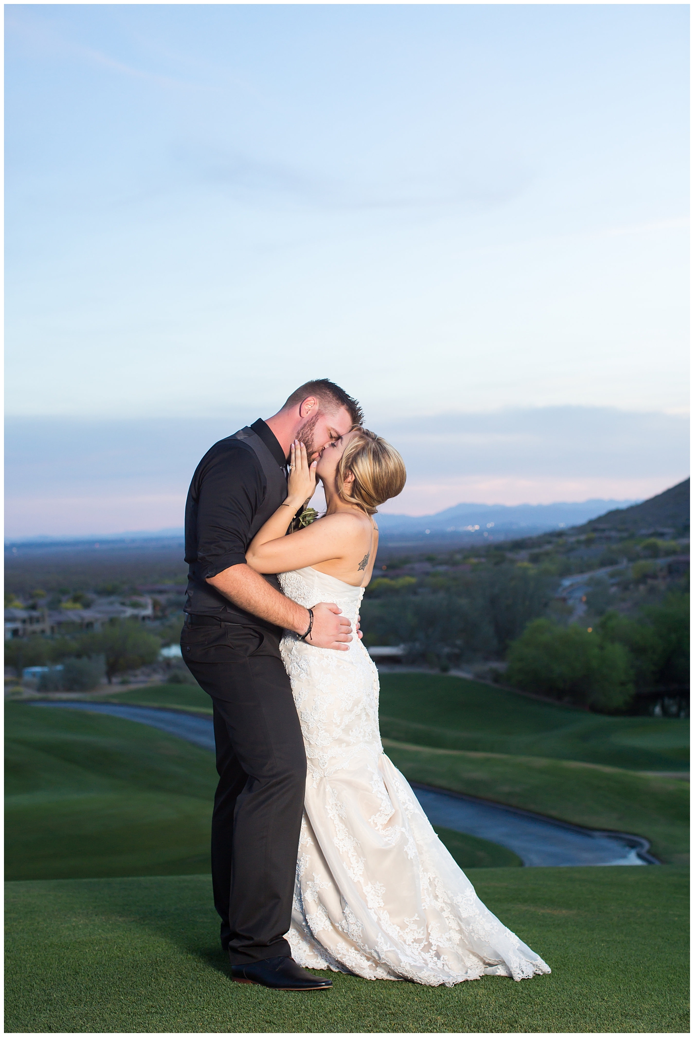bride with fishtail braid and strapless dress with white rose and greenery bouquet with groom in black pants and vest and tie with rolled up shirt sleeves with succulent boutonniere wedding day portrait at sunset