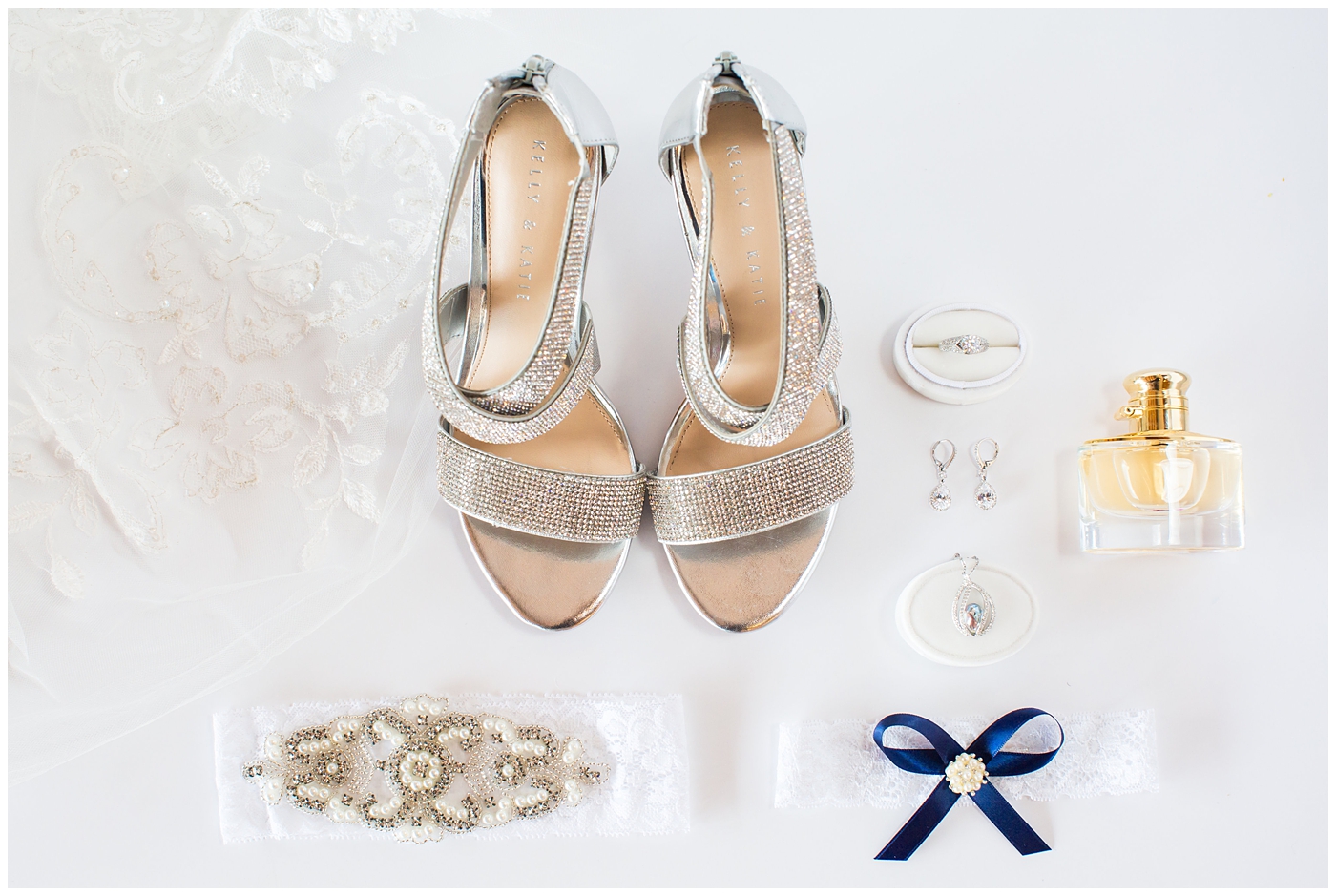 bride details on wedding day flat lay of jewelry, shoes, garter, rings, and perfume