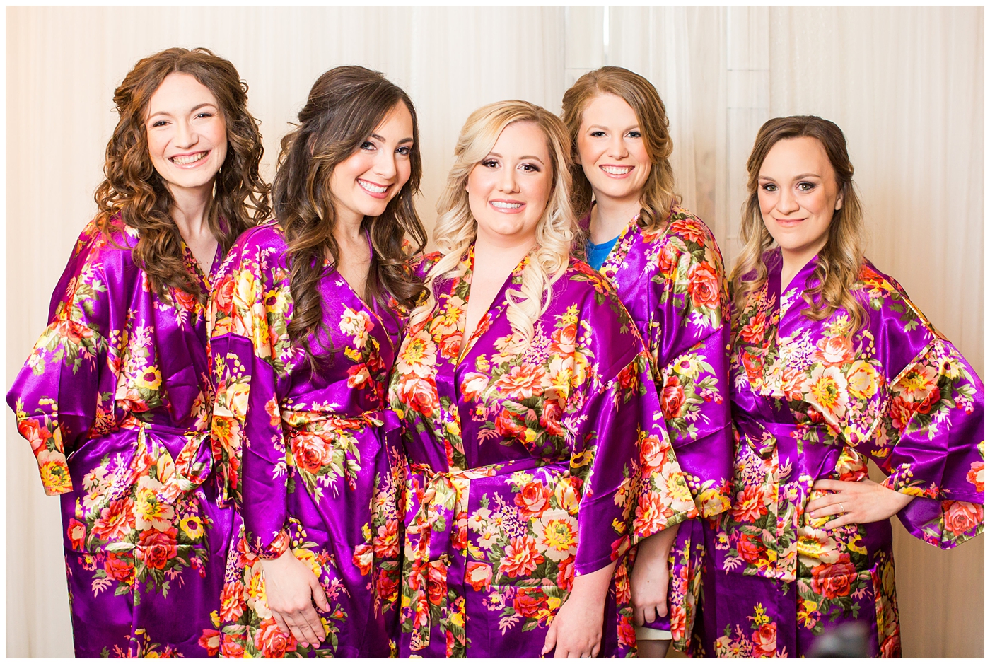 bride with bridesmaids in purple flower silk robes for getting ready on wedding day