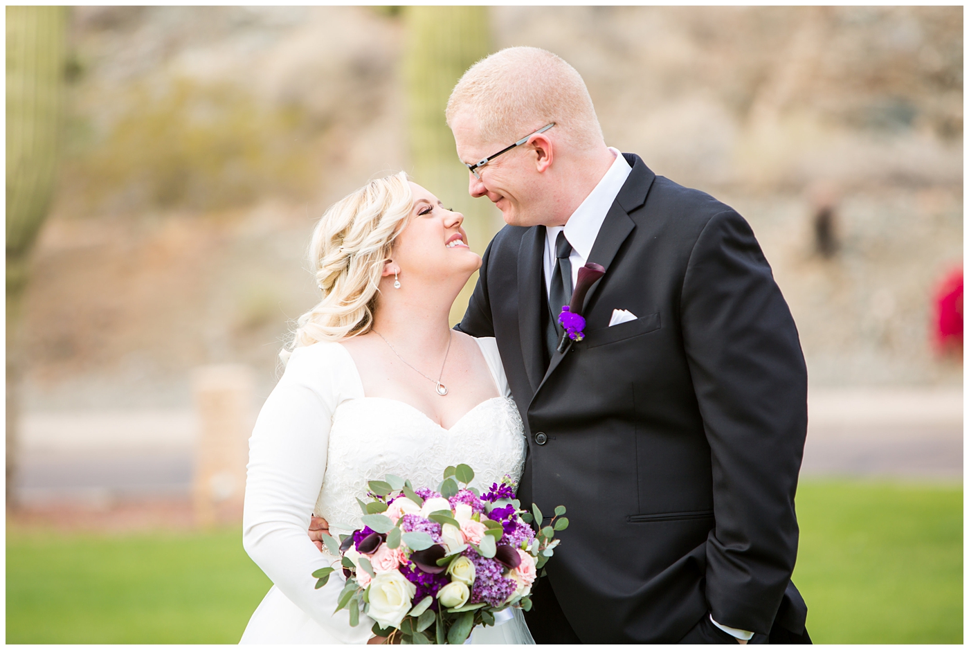 blonde bride in long sleeve wedding dress with purple and white flower bouquet and groom in black suit with purple calla lilly boutonniere wedding day portrait