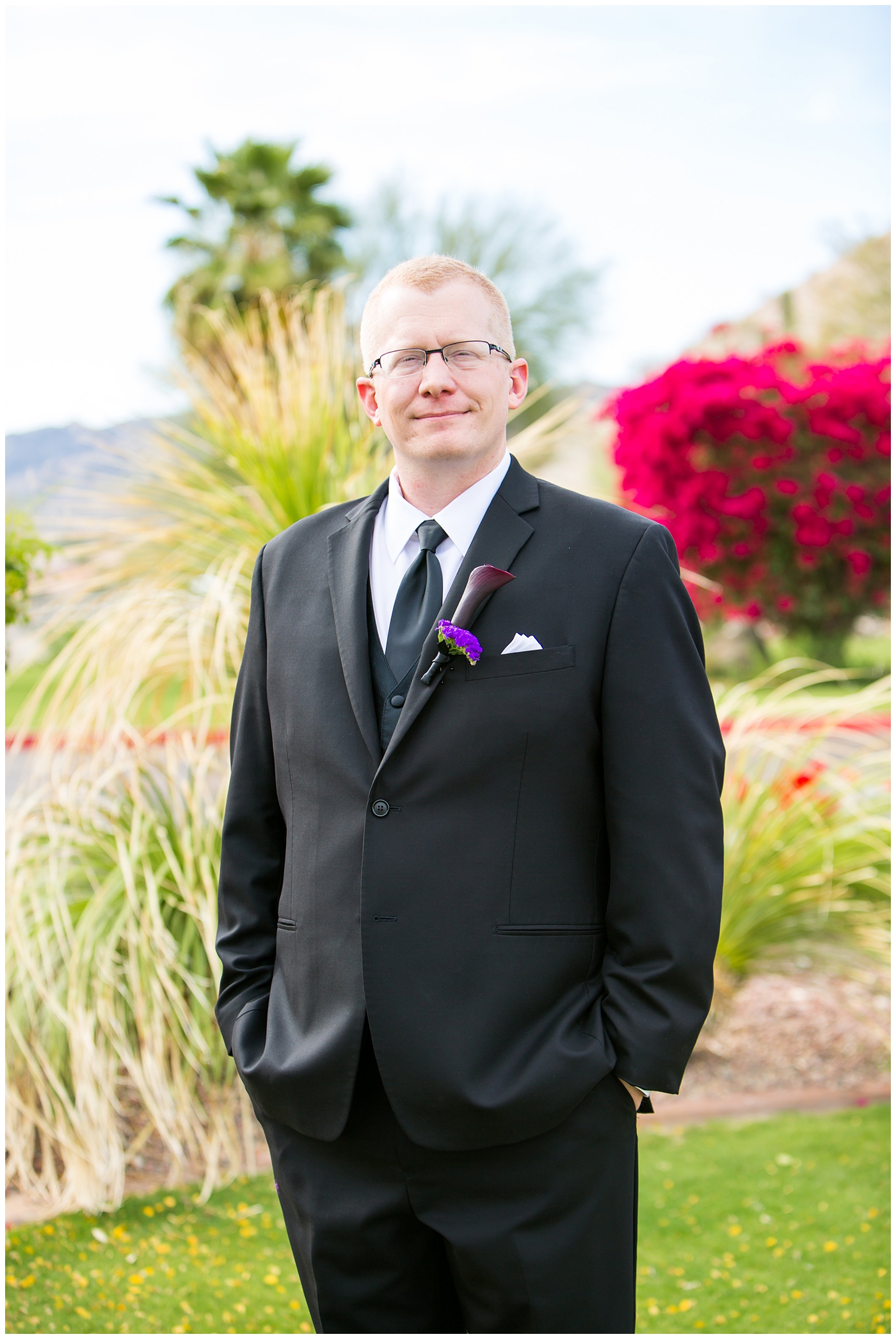 groom in black suit with purple calla lilly boutonniere 
