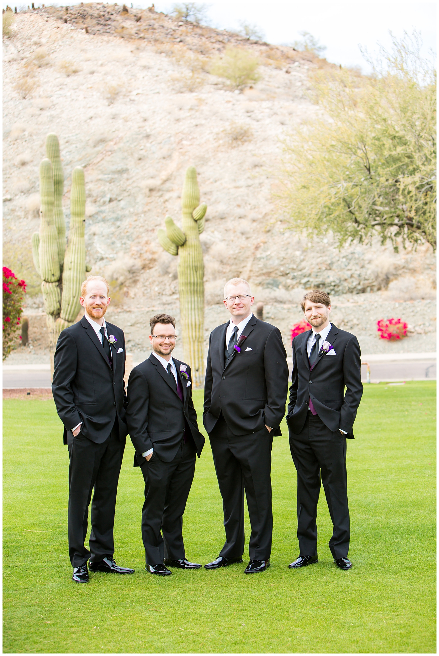 groom in black suit with purple calla lilly boutonniere with groomsmen in black suits with plum vests wedding day bridal party portrait
