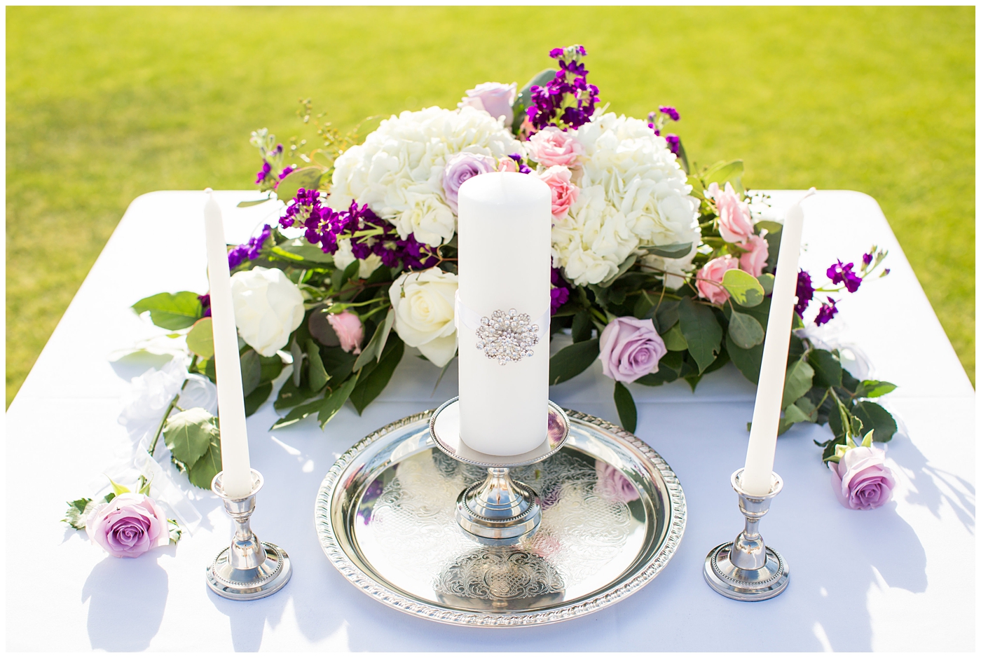 unity candle at golf course outdoor wedding ceremony with white and purple flowers