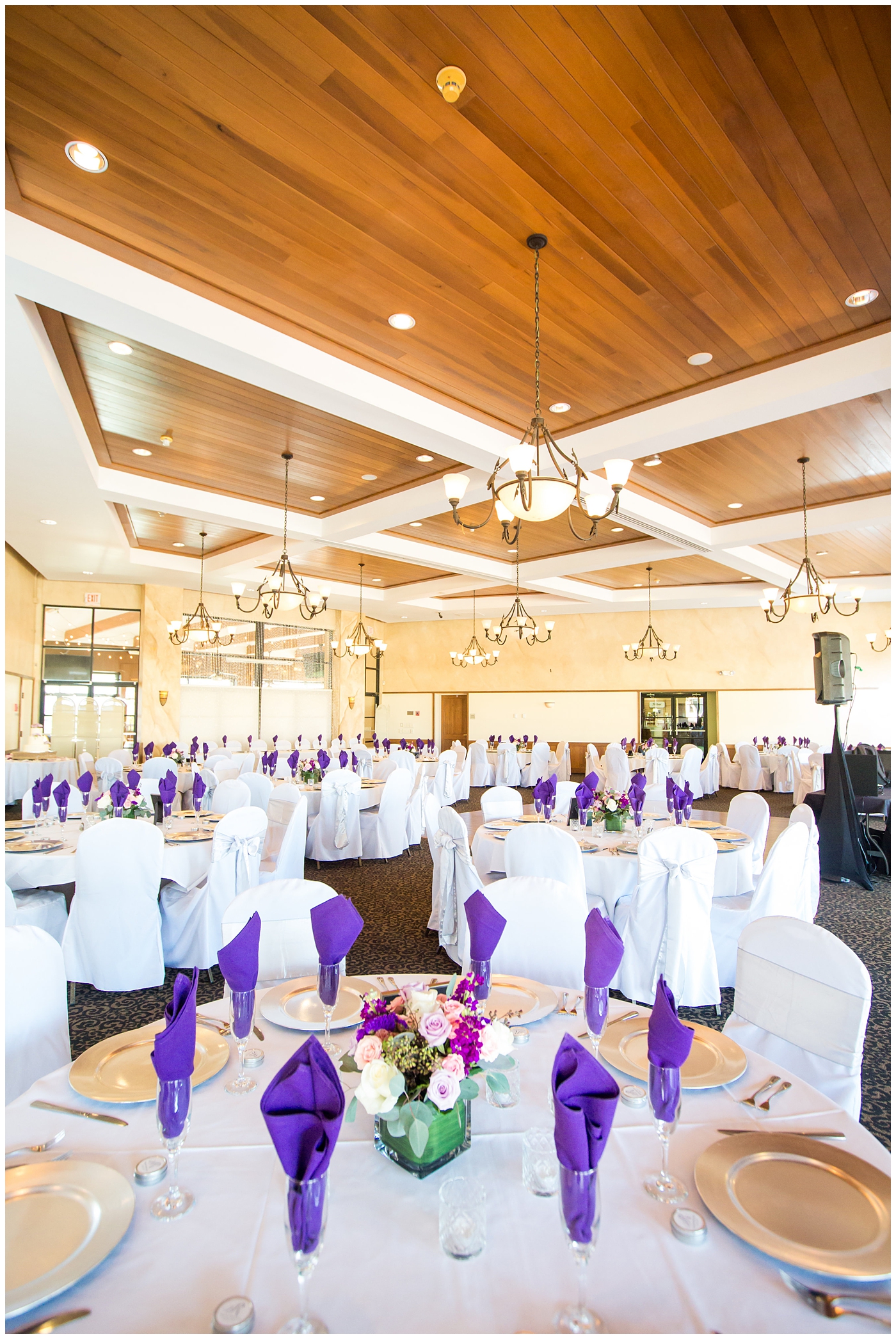 ballroom wedding reception with white chair covers, white table cloths, purple plum naplkins, lavendar roses and greenery centerpieces details