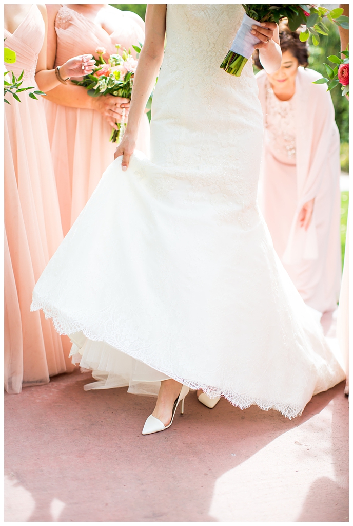 bride in matthew christopher wedding dress with cap sleeves with white, pink and orange ranunculus flowers and greenery bouquet with bridesmaids in blush wedding dresses getting ready on wedding day at Arizona Biltmore