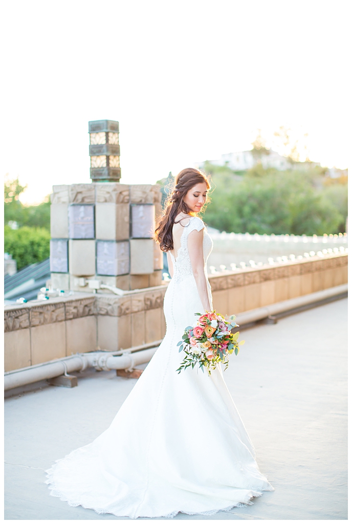 bride in matthew christopher wedding dress with cap sleeves with white, pink and orange ranunculus flowers and greenery bouquet wedding day portrait