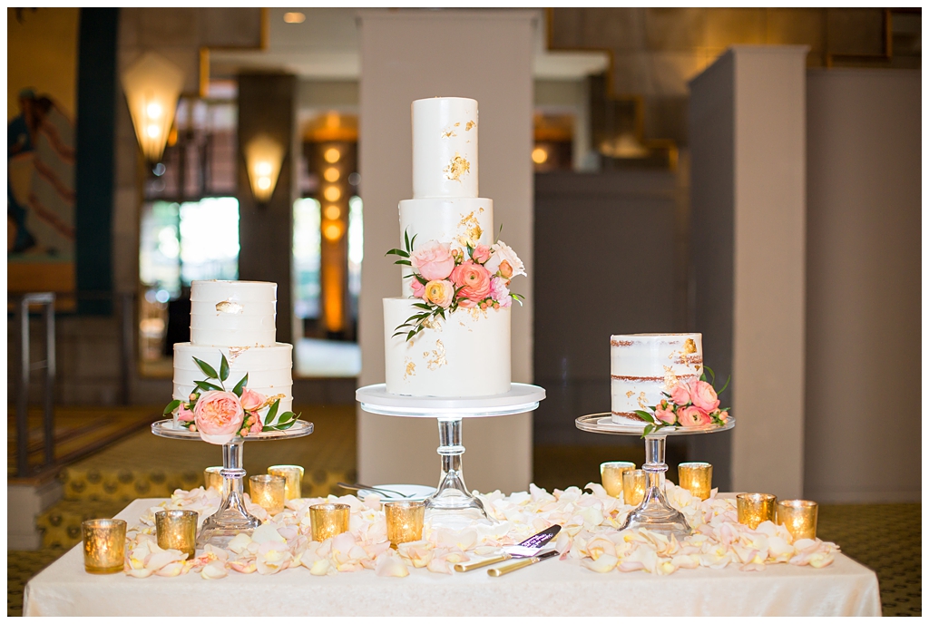 naked wedding cake with pink ranunculus with gold foil