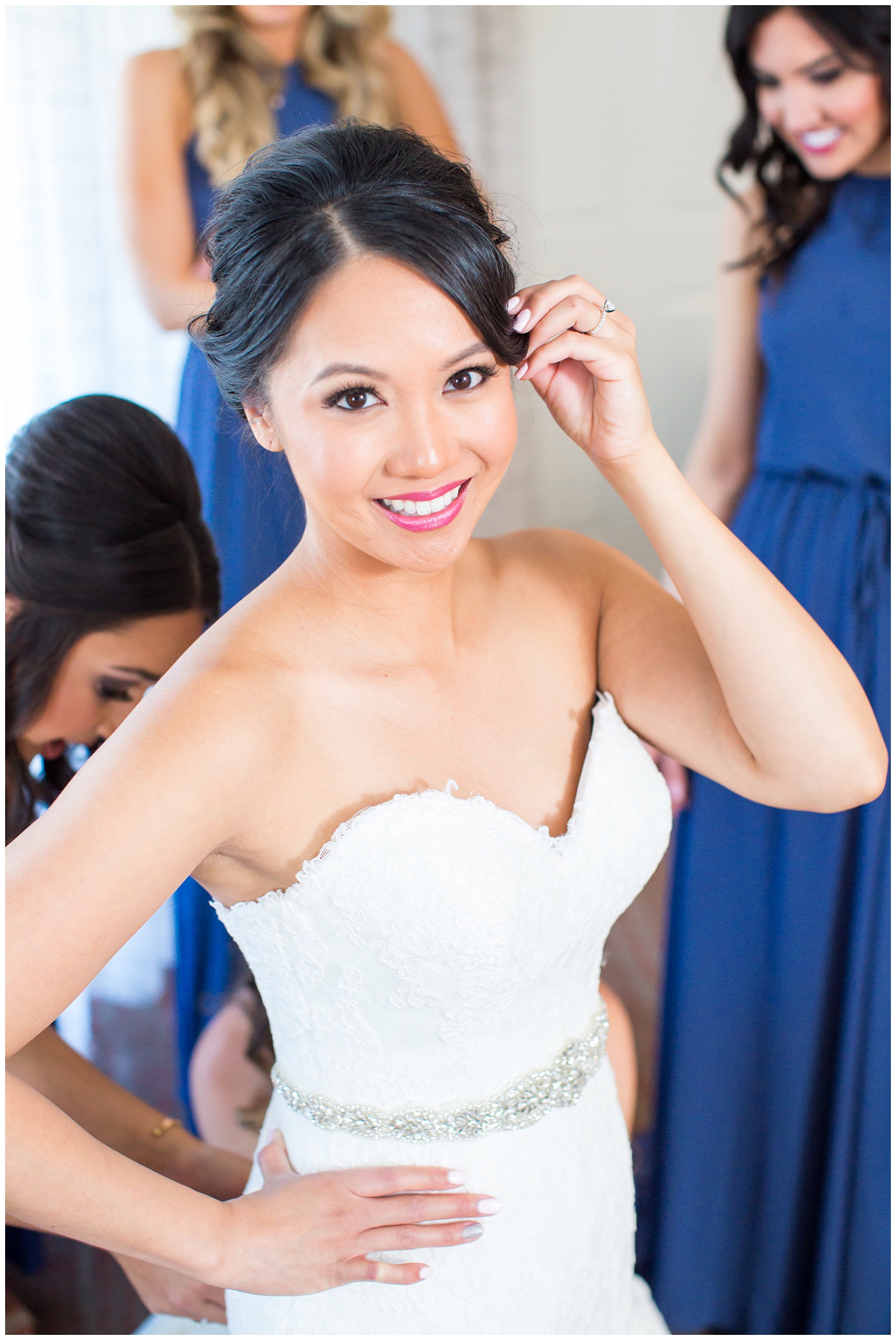 Bride in strapless maggie sorrento dress getting ready with bridesmaids in blue long maxi dresses