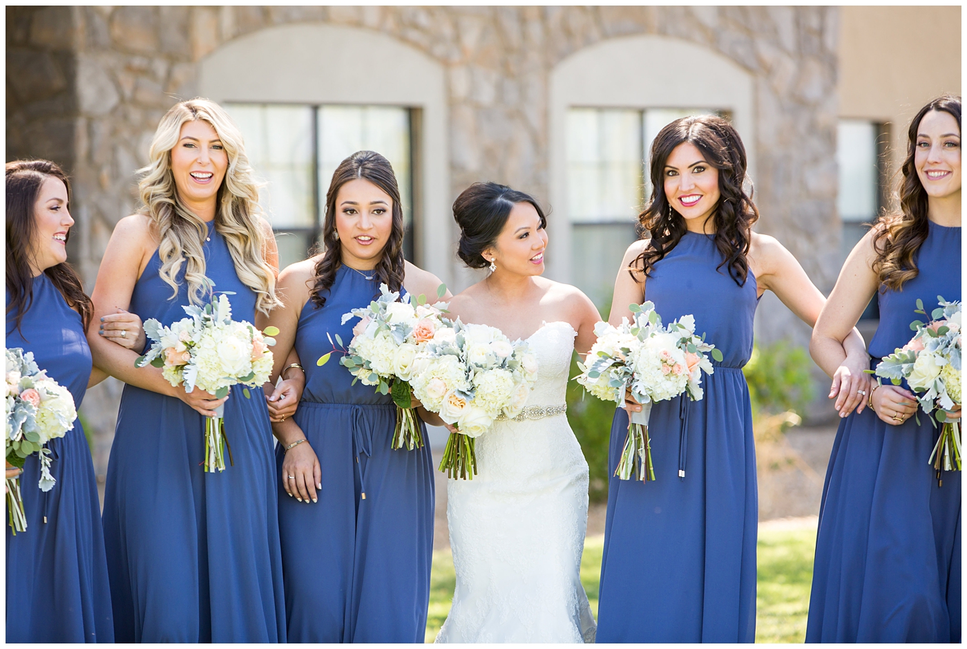 Bride in strapless maggie sorrento dress with soft white and pink roses bouquet with bridesmaids in long blue maxi dresses with bouquets bridal party wedding day pictures