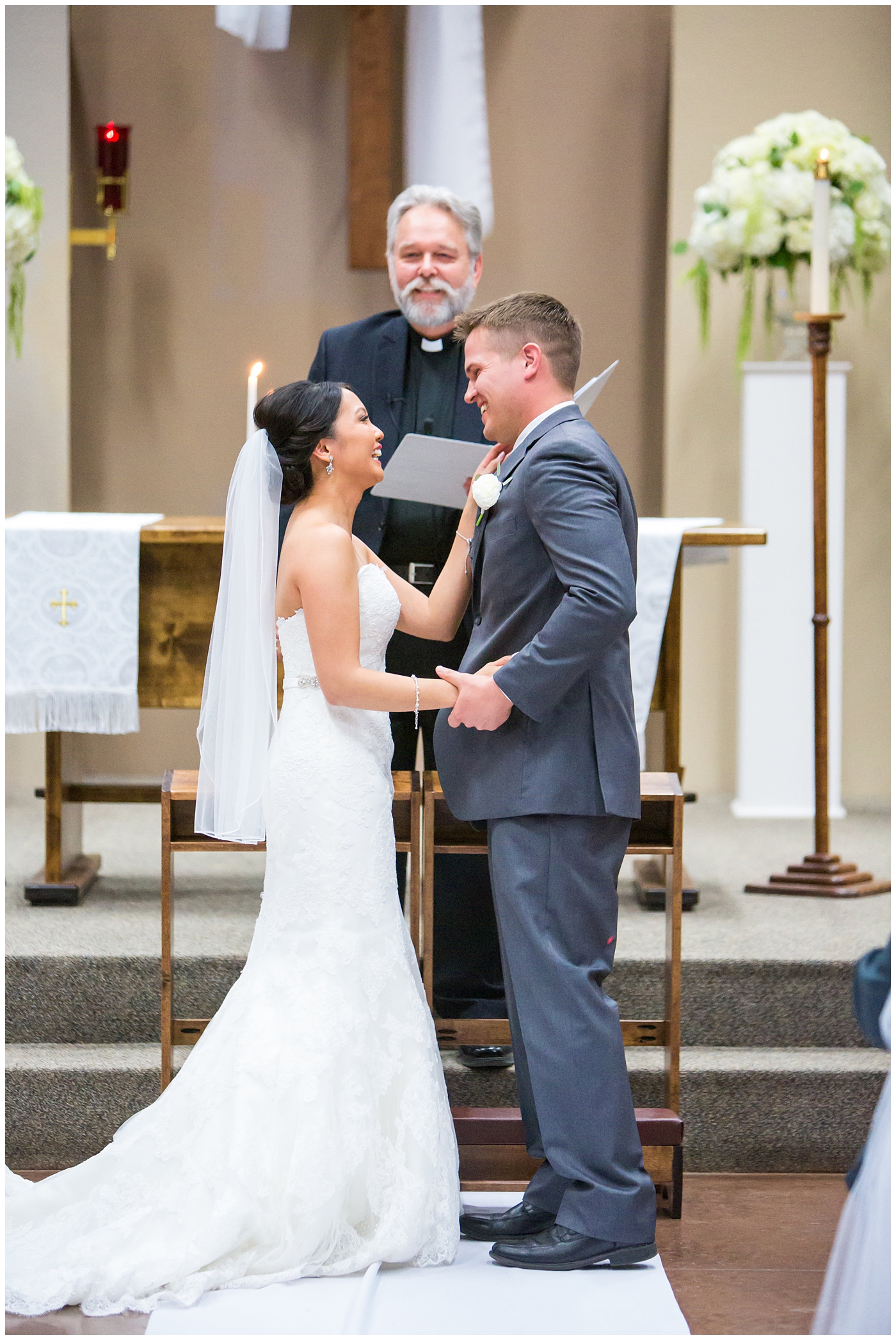 Bride in strapless maggie sorrento dress with soft white and pink roses, peonies, hydrangeas and greenery bouquet with groom in light gray suit with blue tie and white rose boutonniere during church wedding ceremony
