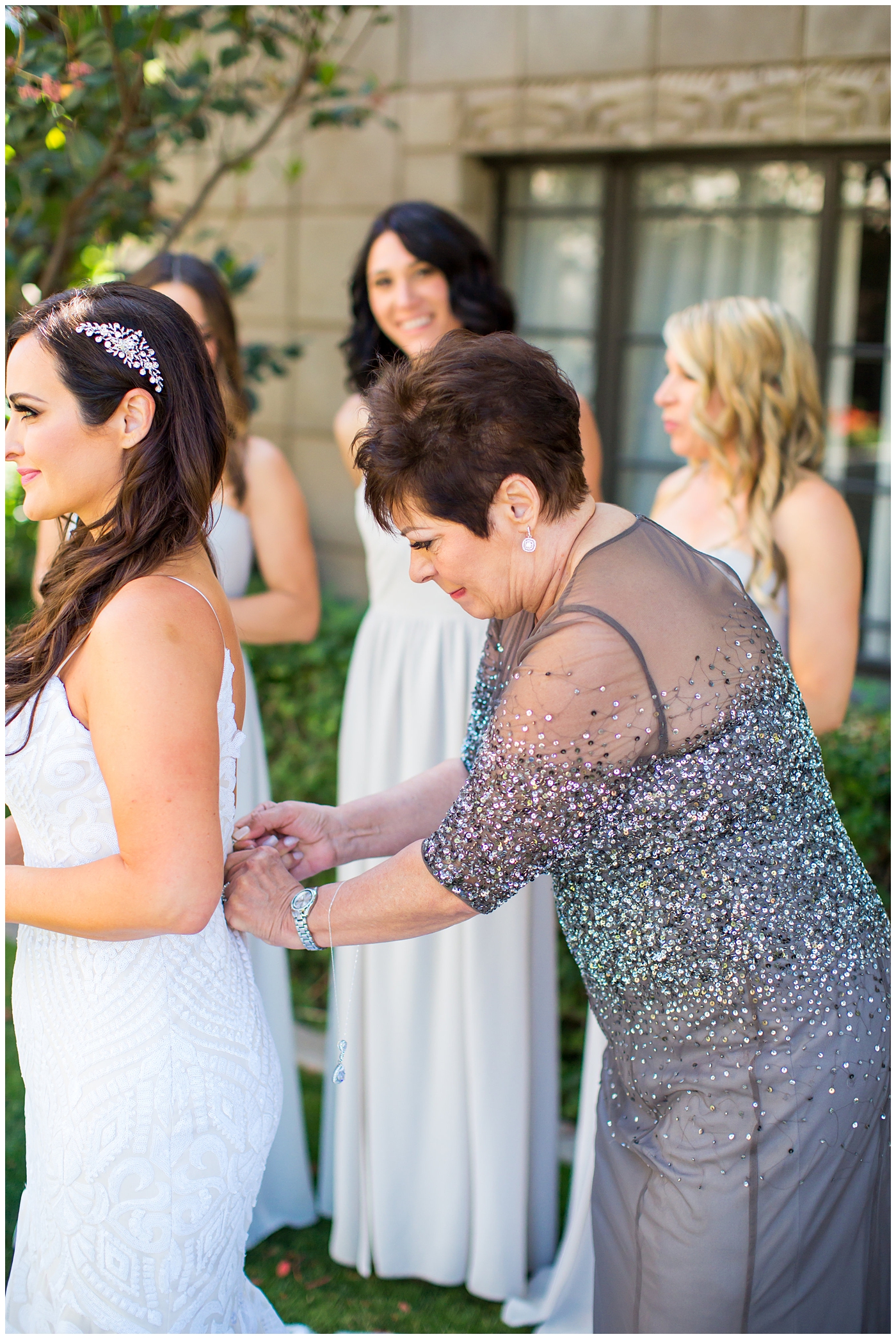 bride in dress with thin straps getting ready with bridesmaids in champagne color dresses