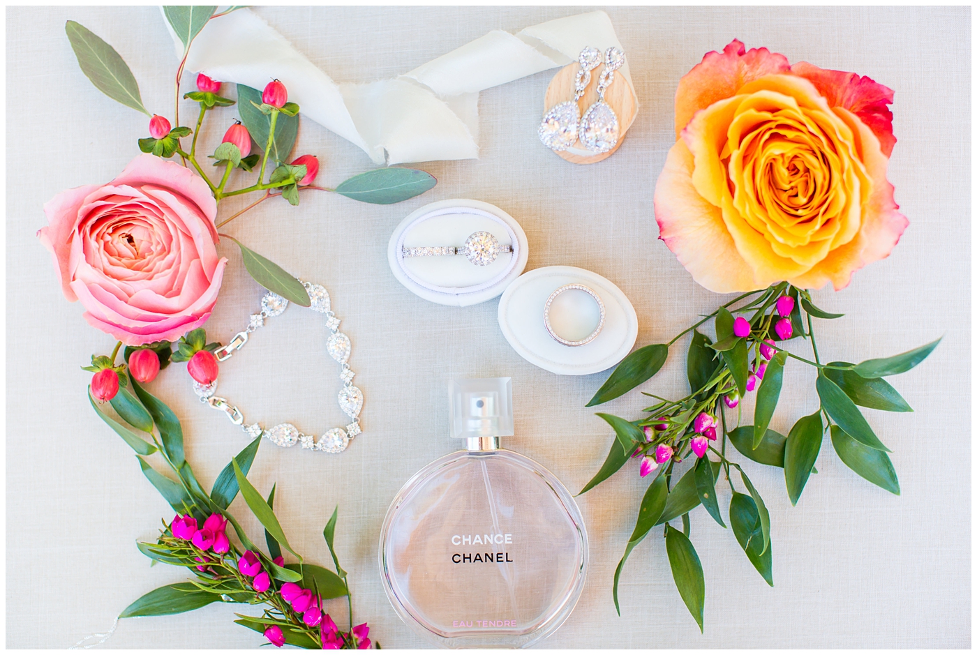 bride's wedding details flat lay with rings, jewelry and perfume
