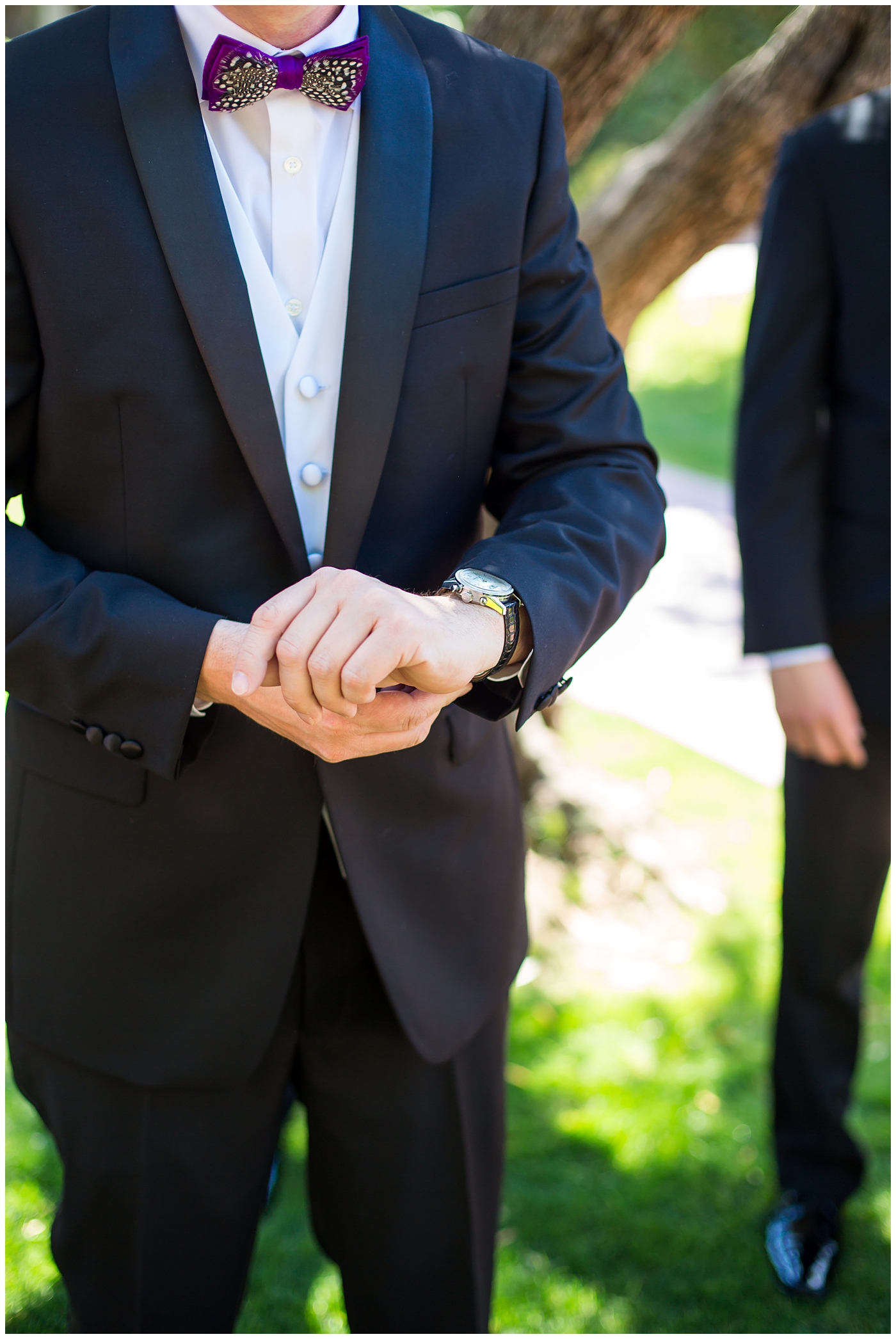 groom in black suit with purple bowtie with black and white feather getting ready with groomsmen on wedding day