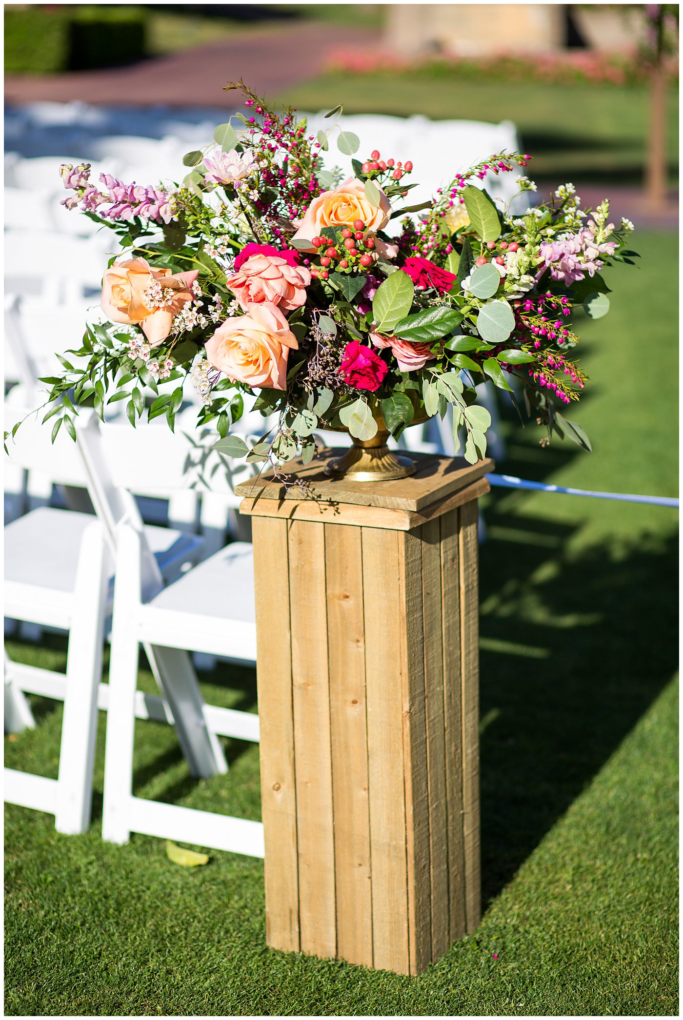 bright color floral arrangement for wedding ceremony on pedestal by aisle 