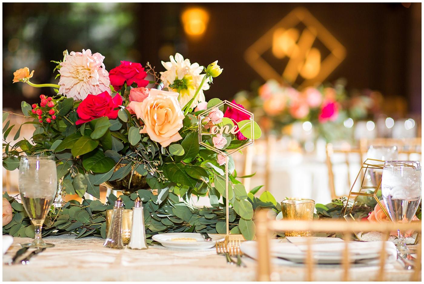 bright pink orange cream floral roses, dahlias centerpieces in gold vases with gold chairs and linens in ballroom wedding reception