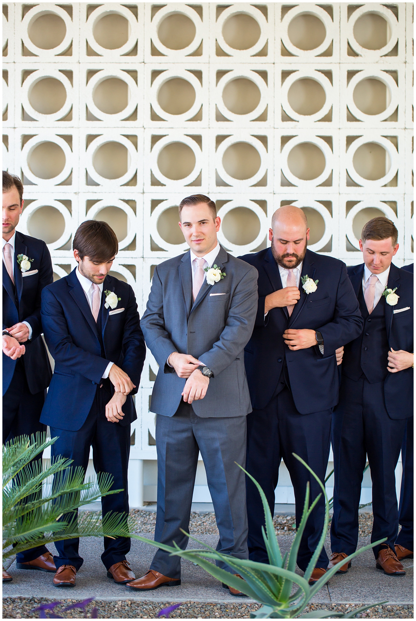 groom in gray suit with pink tie and ranunculus boutonniere and groomsmen in navy suits with pink ties bridal party wedding day portrait