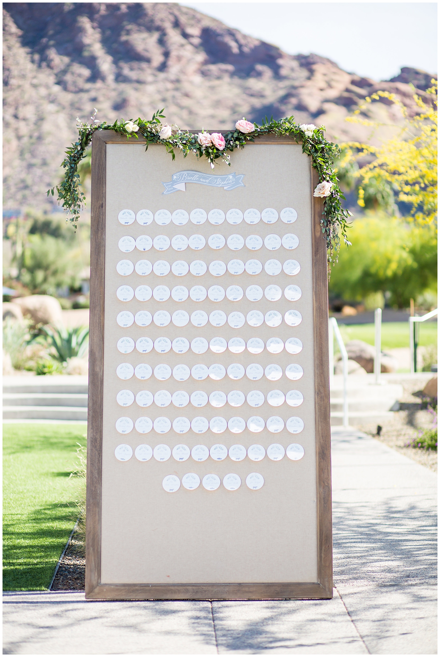 large framed escort card display with greenery across the top and circle cards with entree type symbols