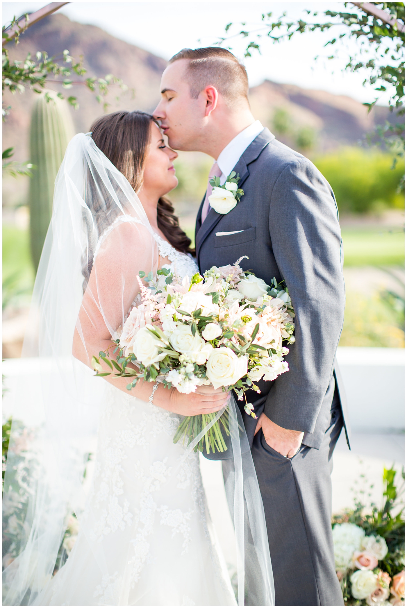 bride in wtoo watters wedding dress with lace straps with wildflower bridal bouquet with soft pink, blush, white, greenery flowers including roses, dahlias, snapdragons with groom in gray suit with pink tie and ranunculus boutonniere with unique circle arch detail for ceremony wedding day portrait