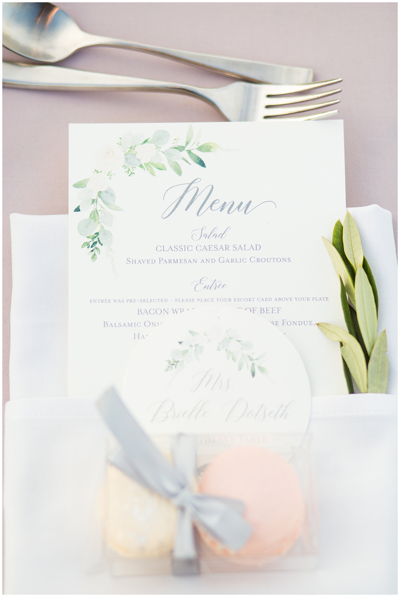 dinner menu for outdoor rooftop wedding reception in folded napkin with sprig of greenery and macaroons for guest gift on blush linen round tables table layout