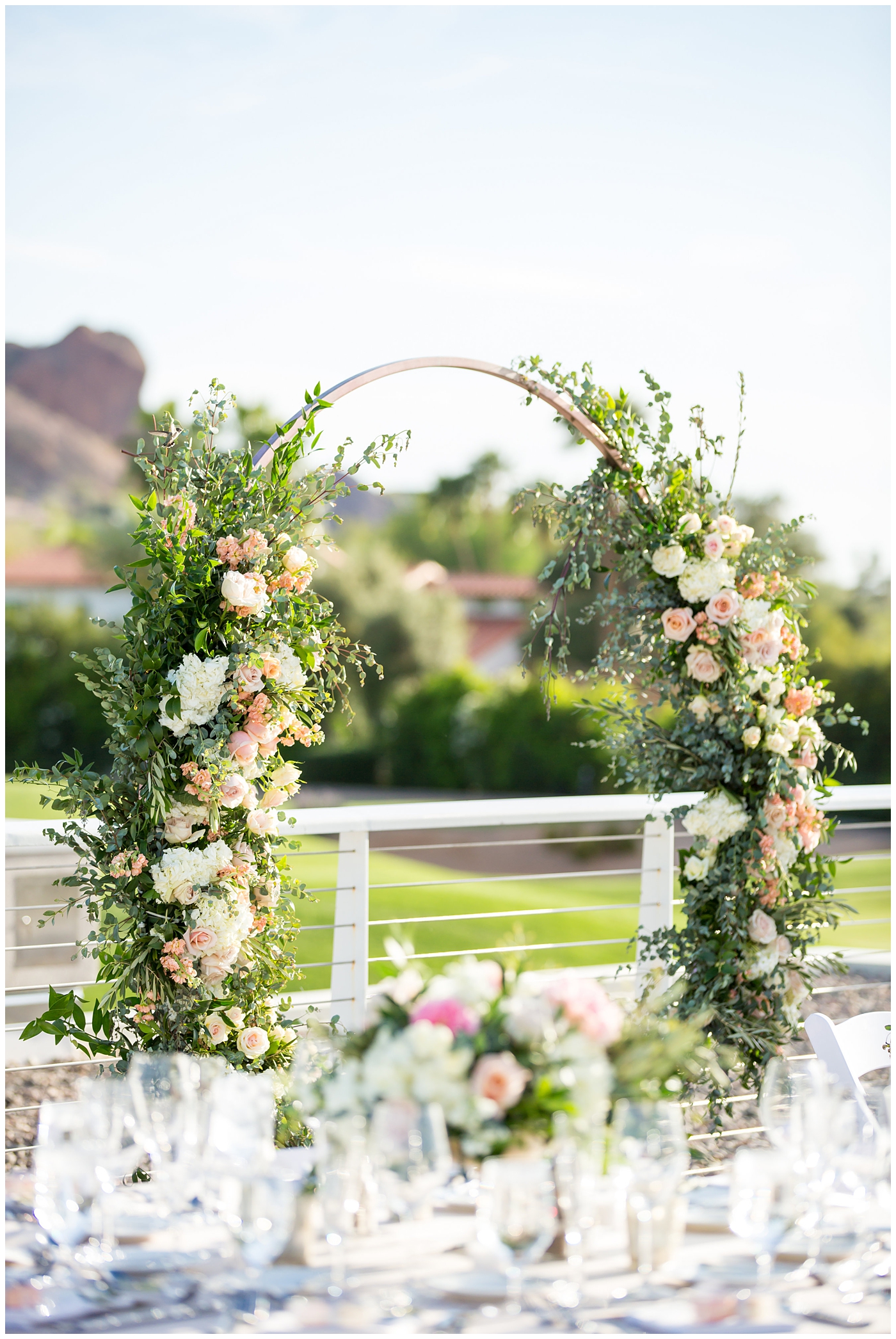 unique circle arch for outdoor rooftop wedding reception with wildflowers in blush and white with greenery with mountain in background