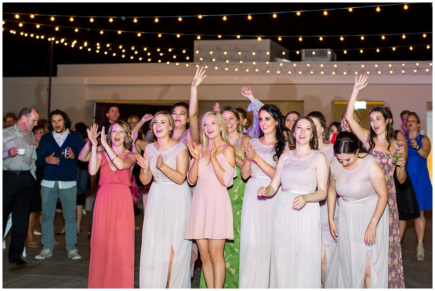 single ladies bouquet toss at rooftop wedding reception with twinkle lights