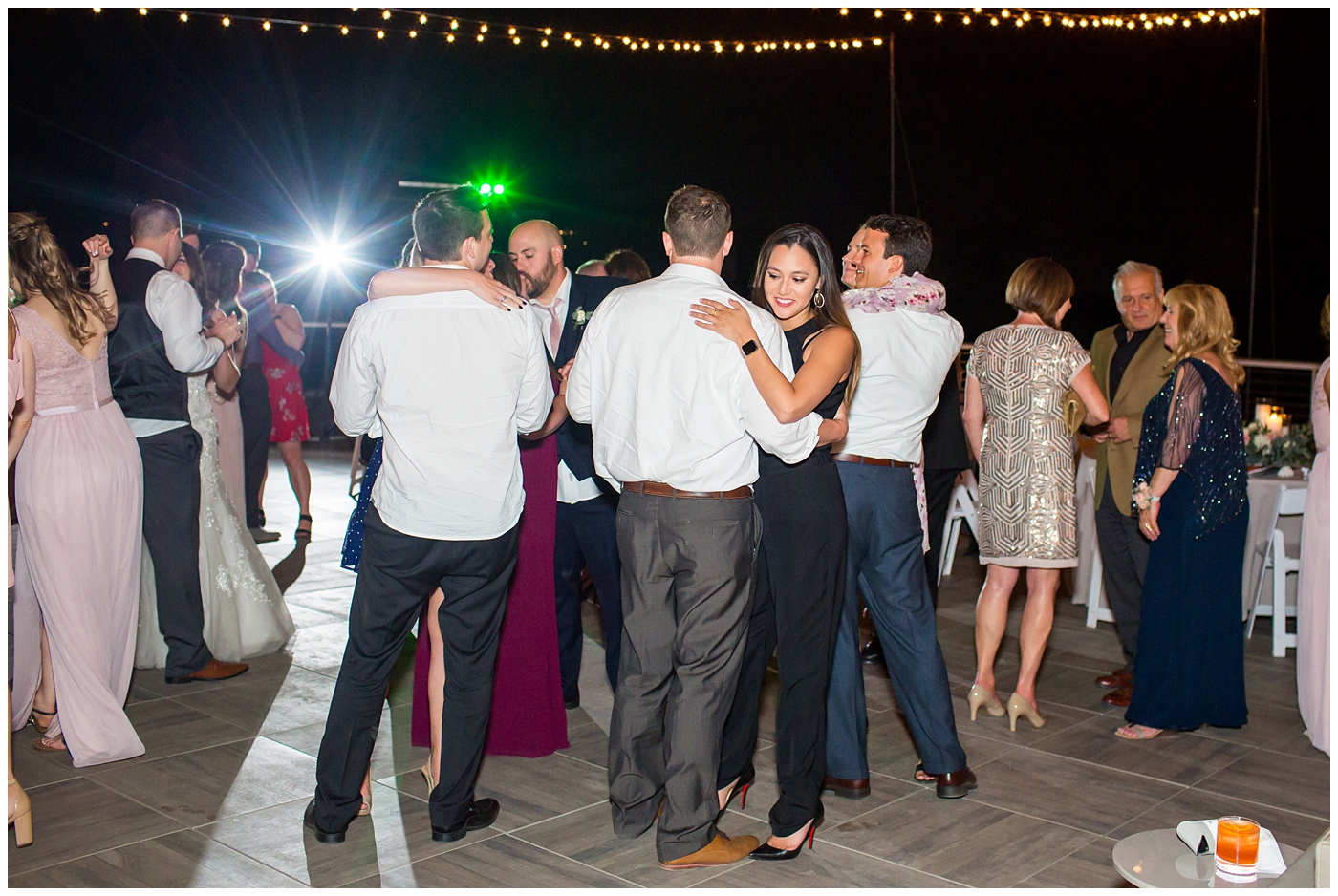guests dancing on rooftop wedding reception with twinkle lights above