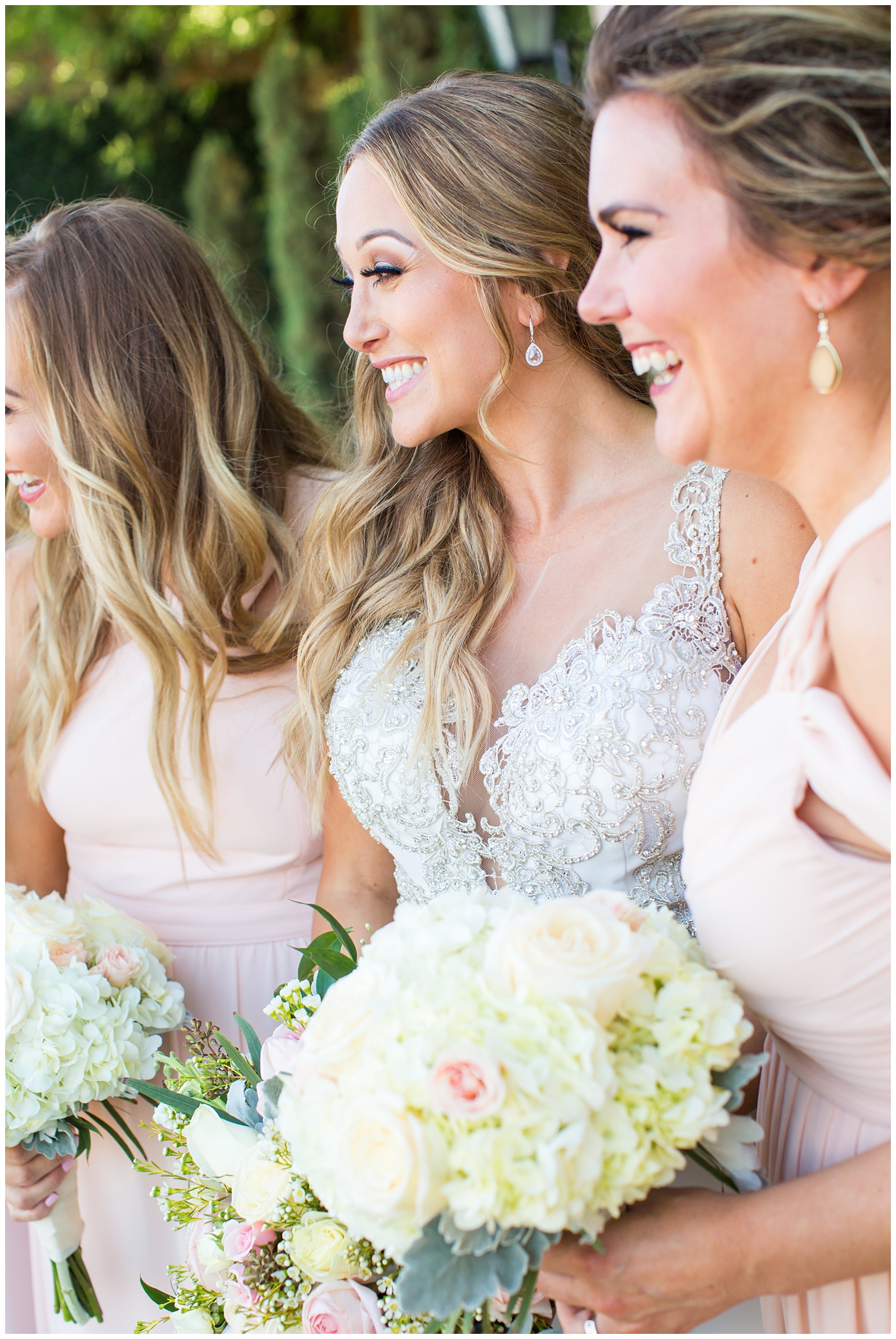 bride in lillian lottie couture strapped beaded wedding dress getting ready on wedding day with bridesmaids in long blush dresses