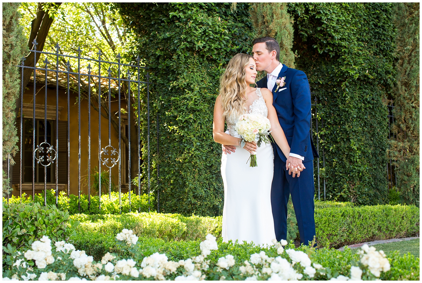 bride in lillian lottie couture strapped beaded wedding dress with organic blush, white and greenery bouquet with groom in blue suit with rose boutonniere wedding day portrait 