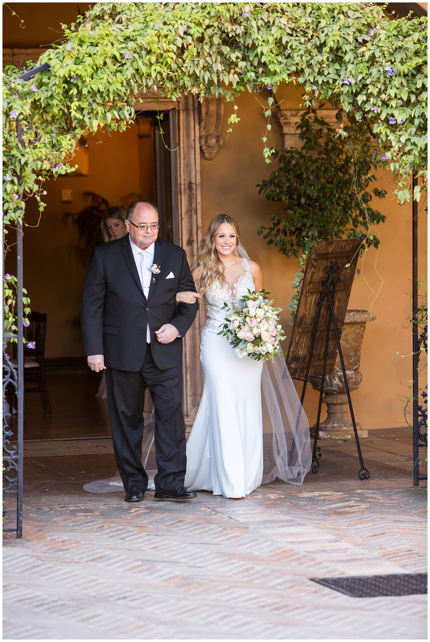 bride in lillian lottie couture strapped beaded wedding dress with organic blush, white and greenery bouquet walking down the aisle with father at outdoor wedding ceremony