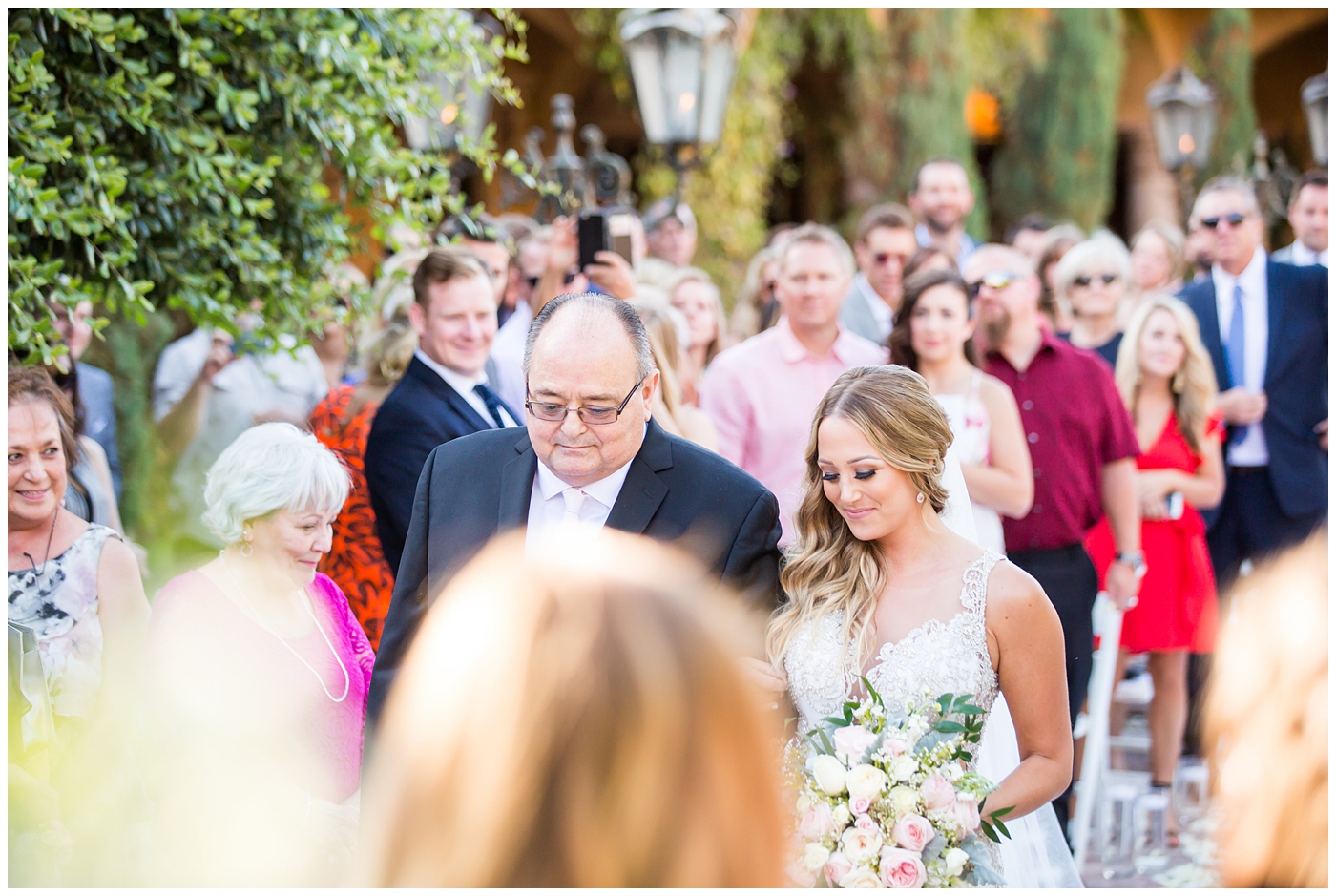 bride in lillian lottie couture strapped beaded wedding dress with organic blush, white and greenery bouquet walking down the aisle with father at outdoor wedding ceremony