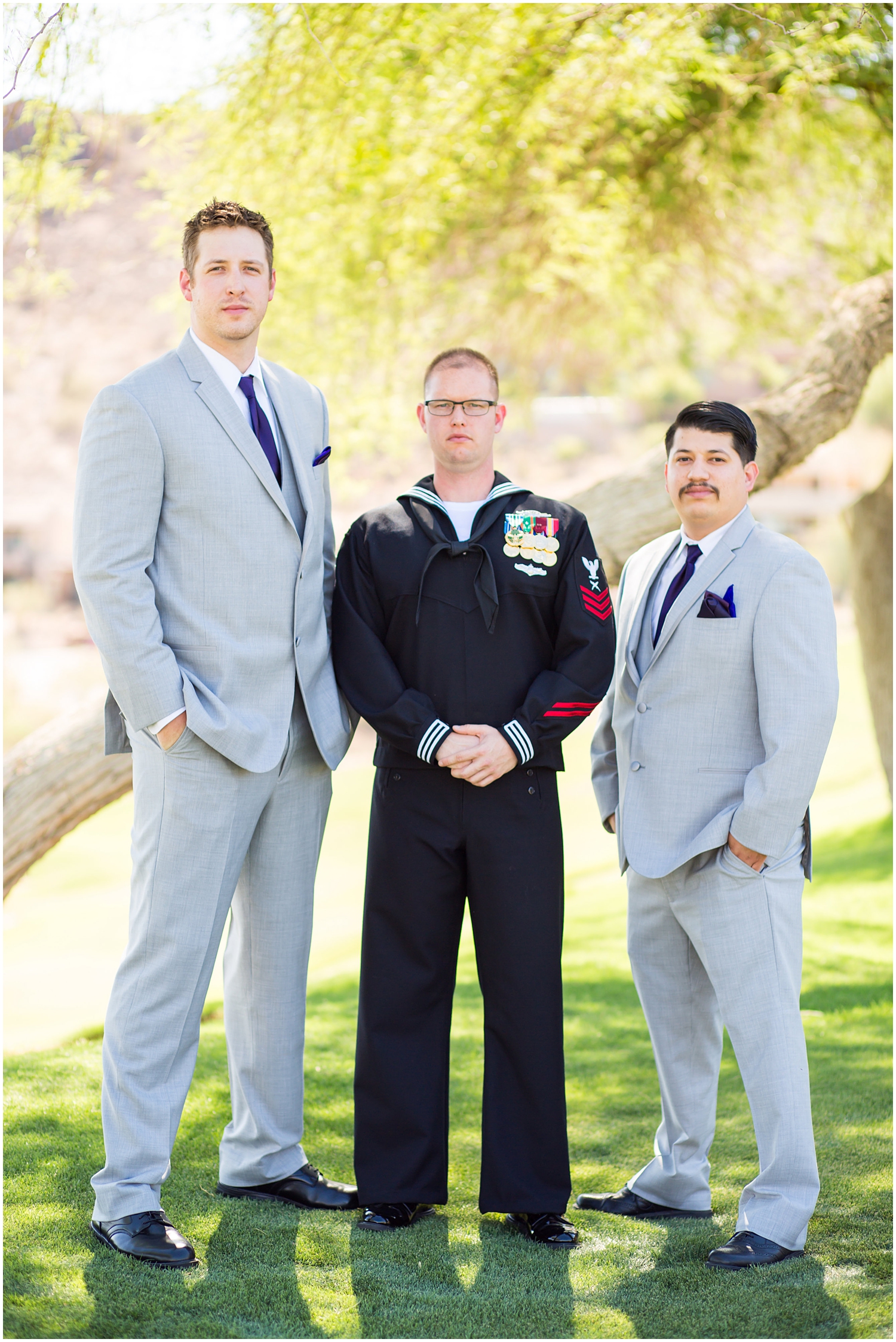 Groom in Navy dress uniform with groomsmen in light grey suits and purple tie on wedding day 