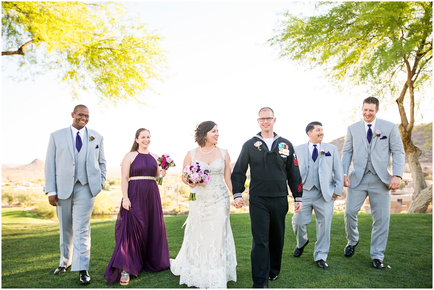 bride in strapless dress with veil and purple lavender peony and rose bouquet with bridesmaid in dark purple maxi dress and bridesman in light grey suit with Groom in Navy dress uniform with groomsmen in light grey suits and purple tie on wedding day wedding party group shot
