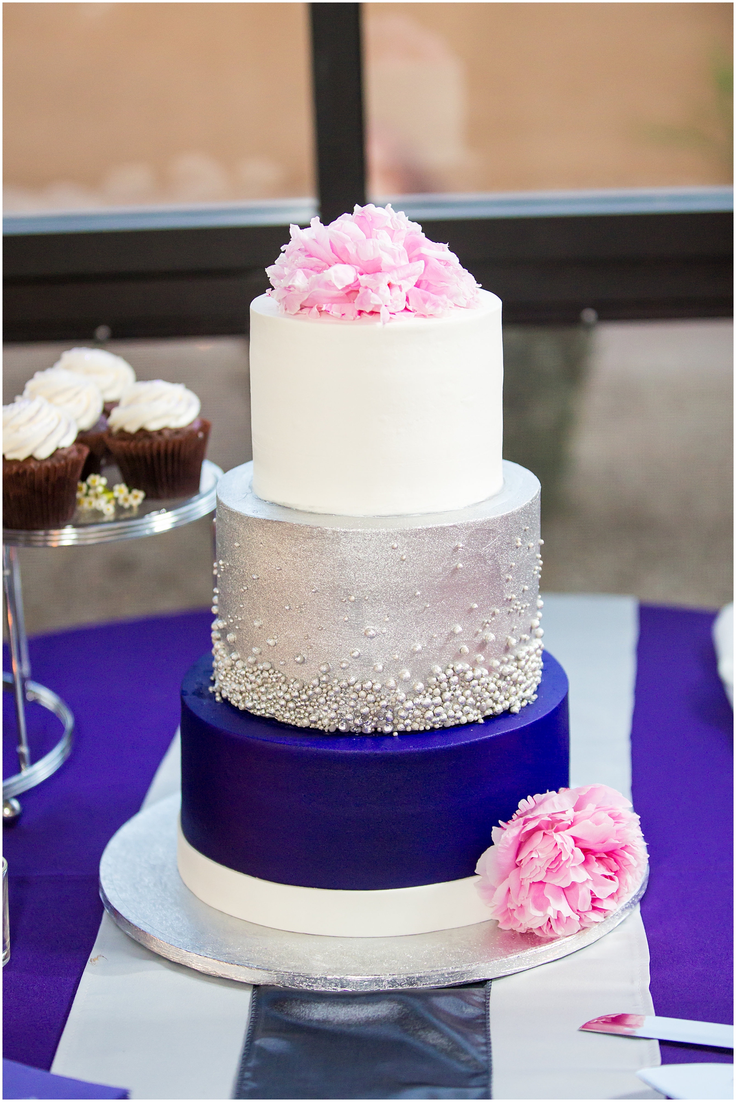three tier wedding cake with peony on it, one dark purple and silver