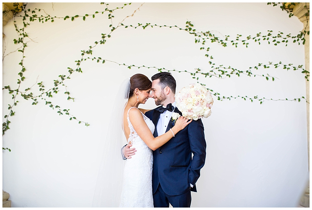 Bride & Groom in front of white green ivy wall at Montelucia