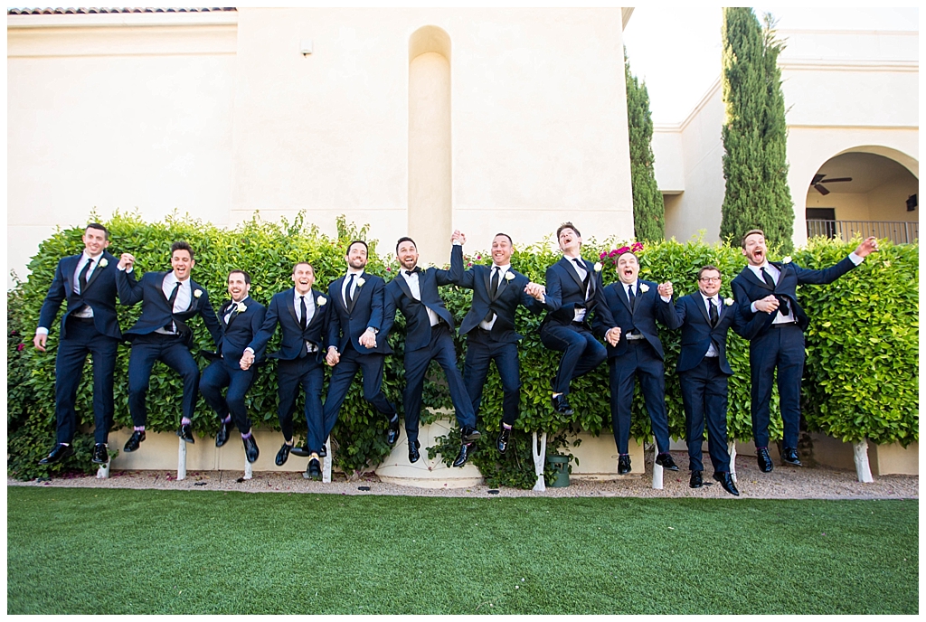 Groom and groomsmen jumping in navy blue suits at Omni Montelucia