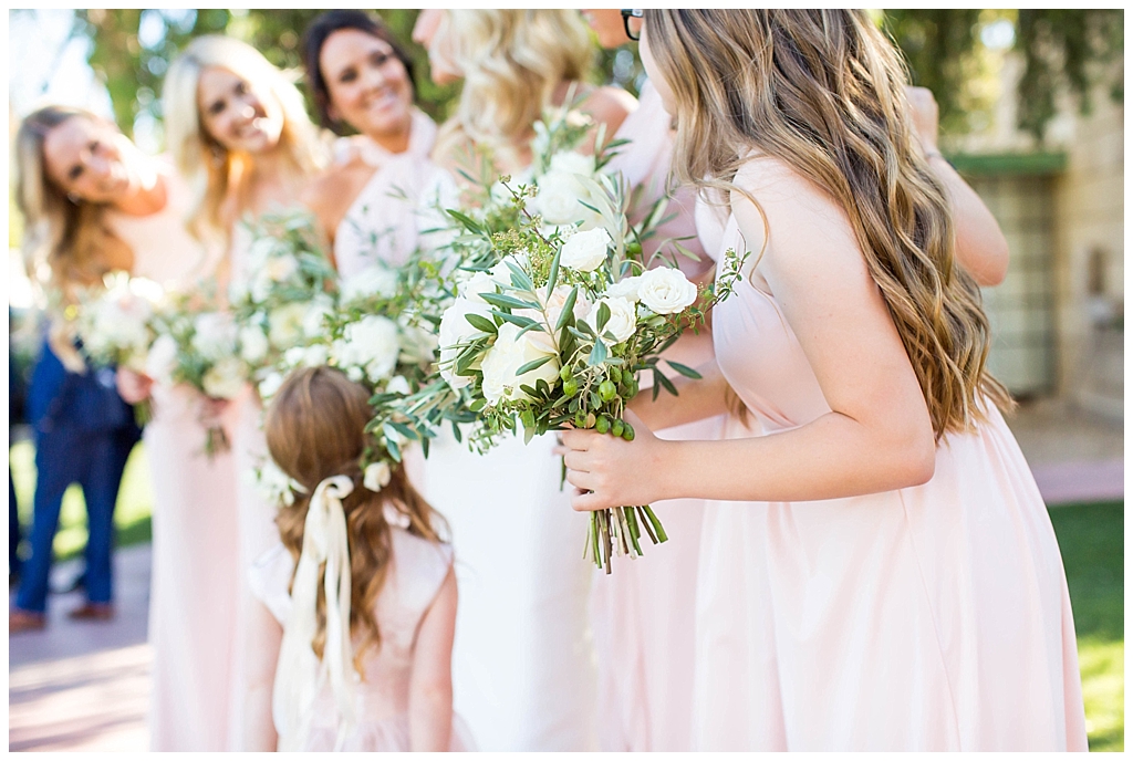 white floral bouquet with greenery and bridesmaids in blush dresses