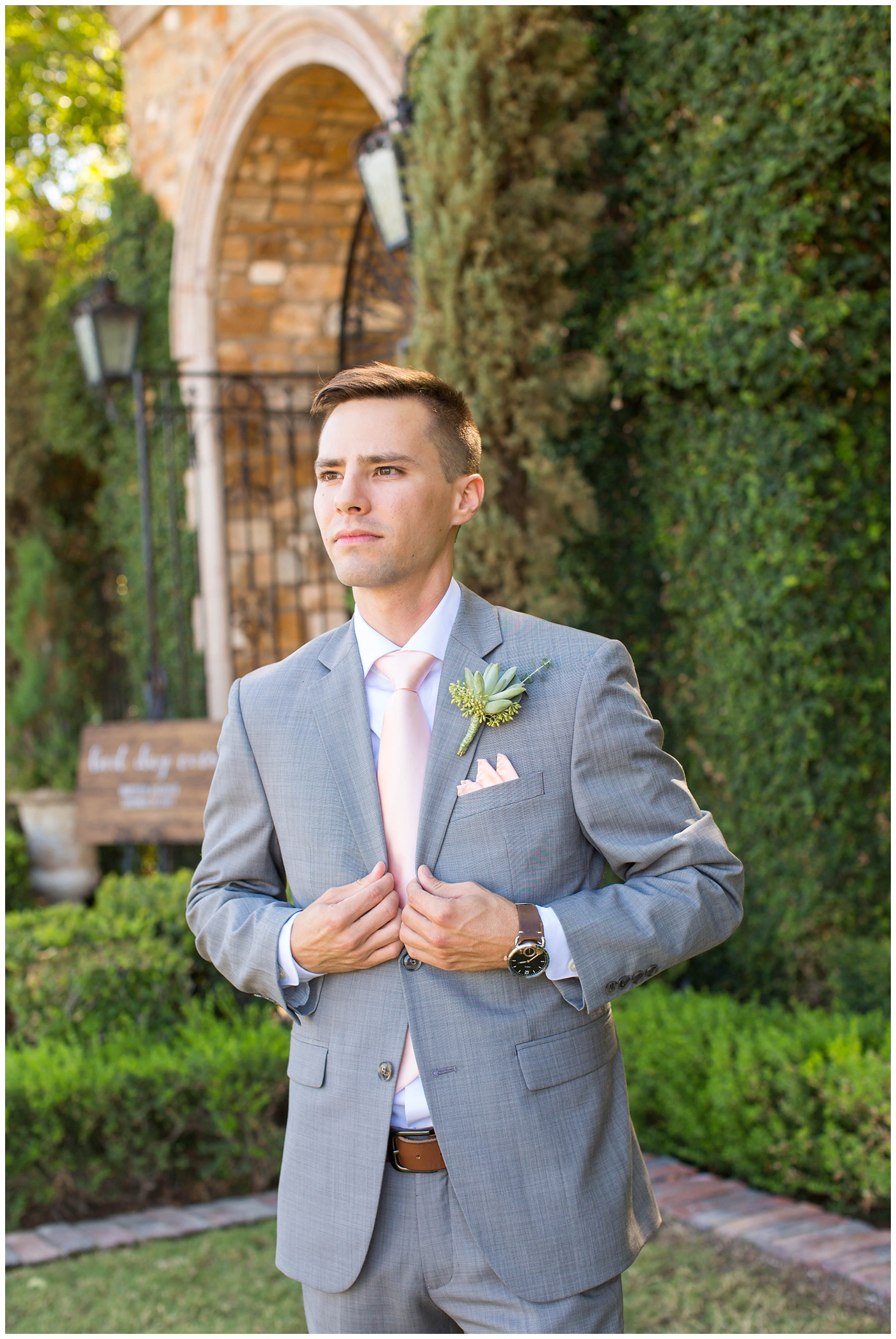 handsome groom buttoning up his gray jacket