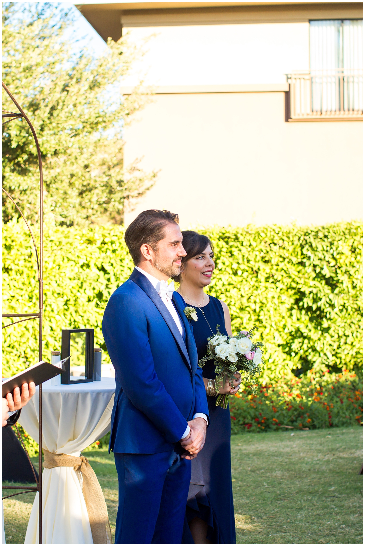 Groom in a custom Brother's Tailors Blue suit waiting for bride at ceremony