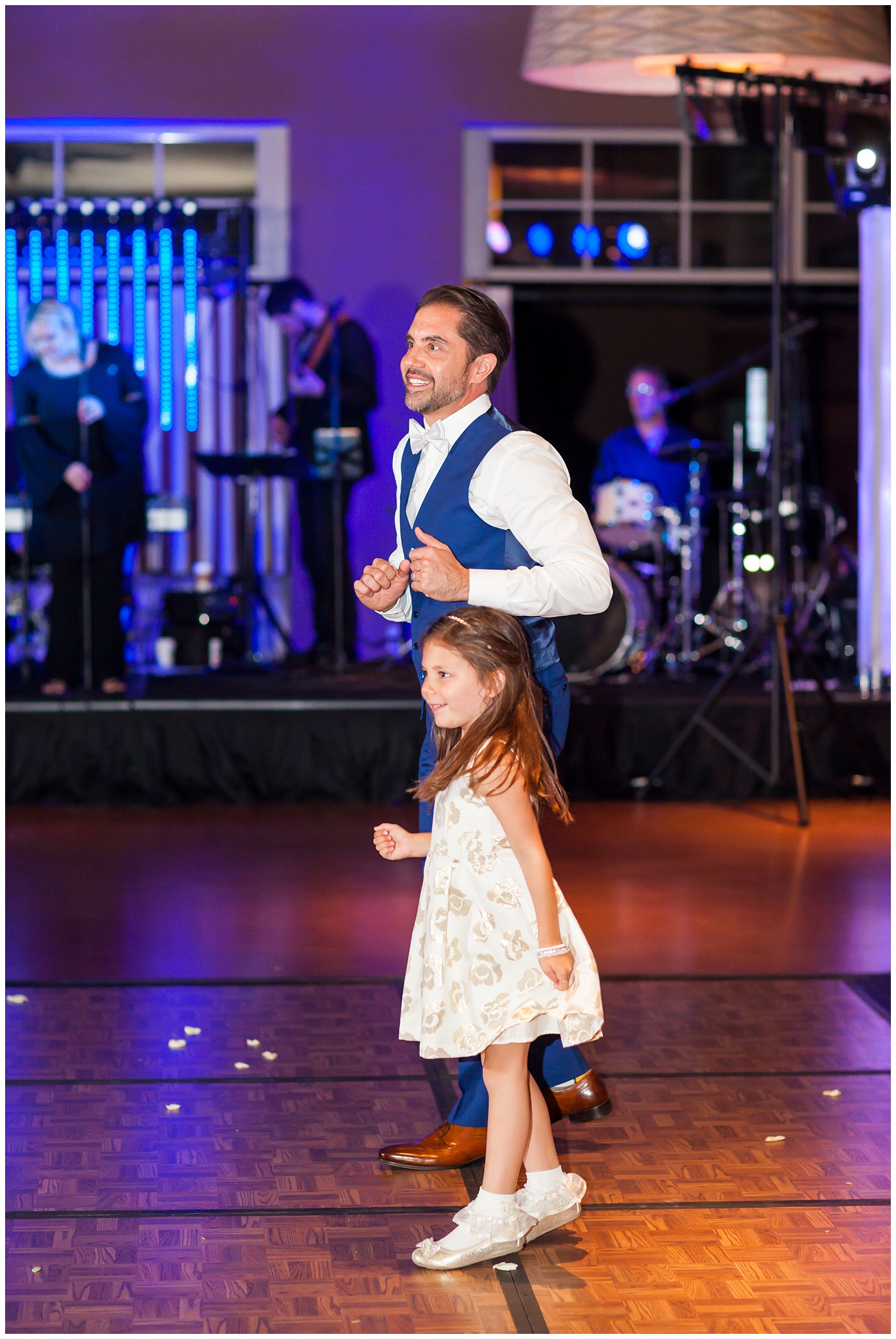 Groom in a custom Brother's Tailors Blue suit dancing with flowergirl