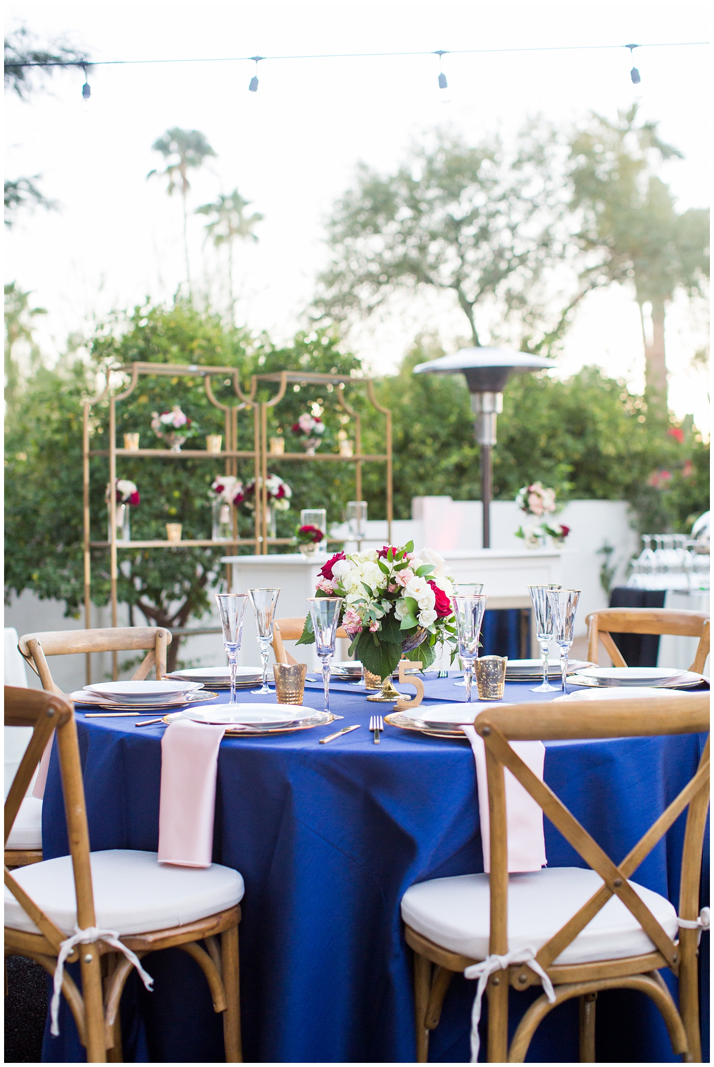 reception details tables with blue linens, gold table numbers and candles with white and red rose centerpieces