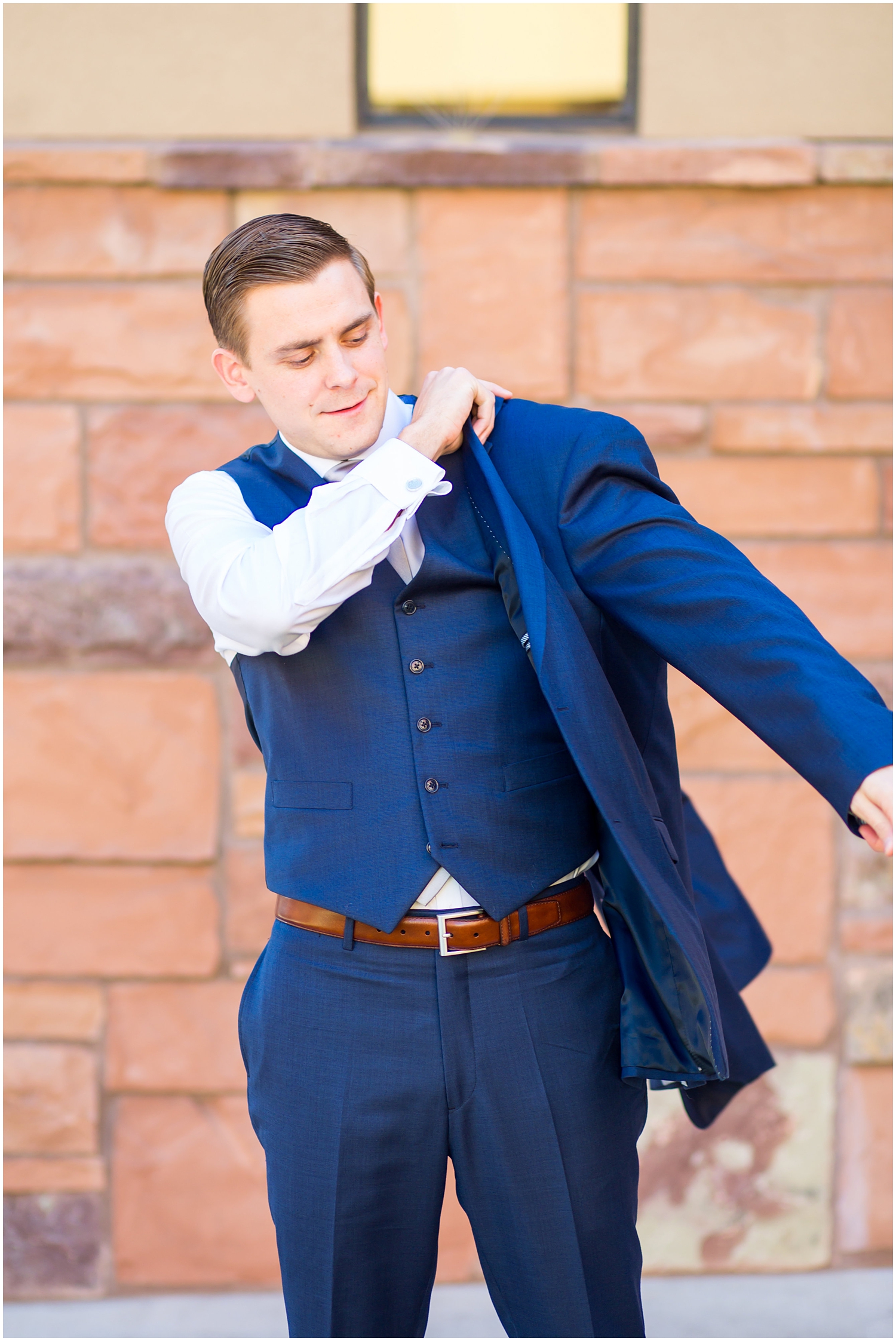 groom in navy blue suit with light blue tie getting ready on wedding day